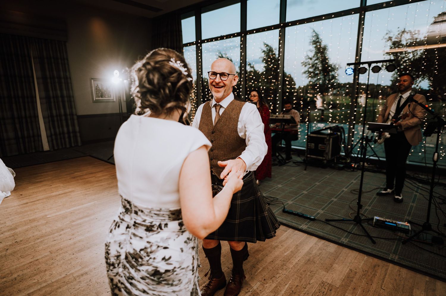 Reception venue with large windows and dance floor setup for evening celebration. Meldrum House Wedding Photography.