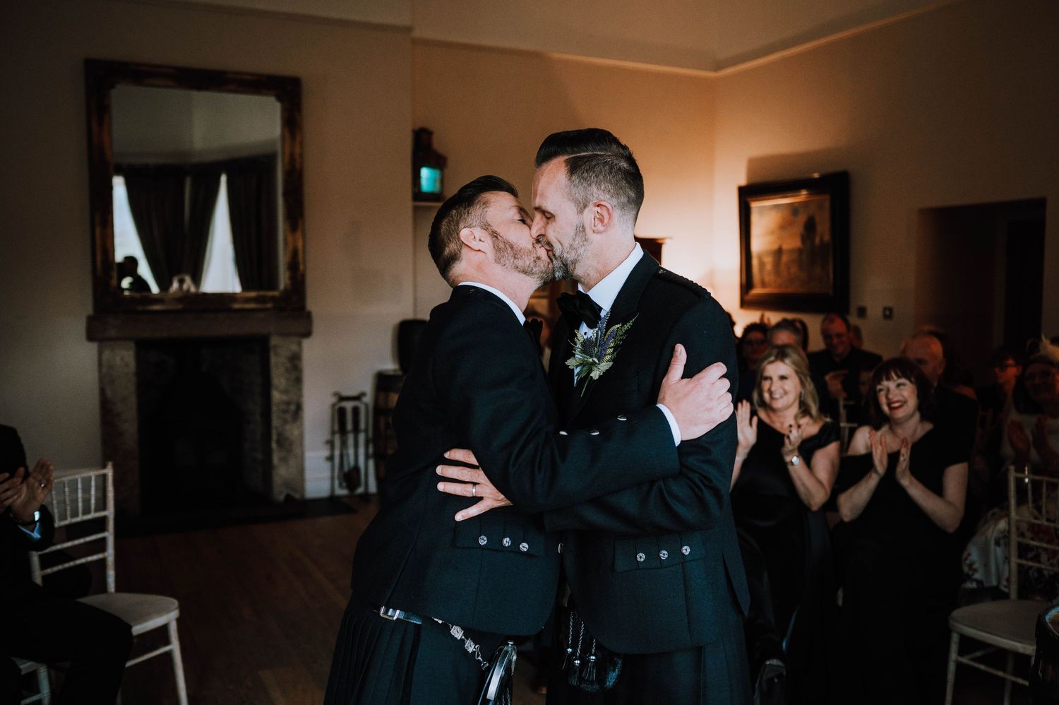 Logie House Wedding Photography. A dimly lit wedding reception shows guests in formal attire celebrating together.