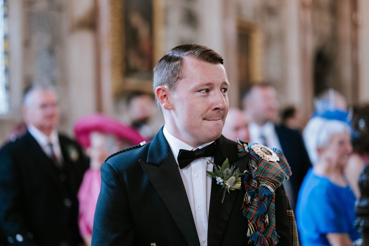 Wedding guests smile and celebrate during an indoor ceremony at an elegant venue.