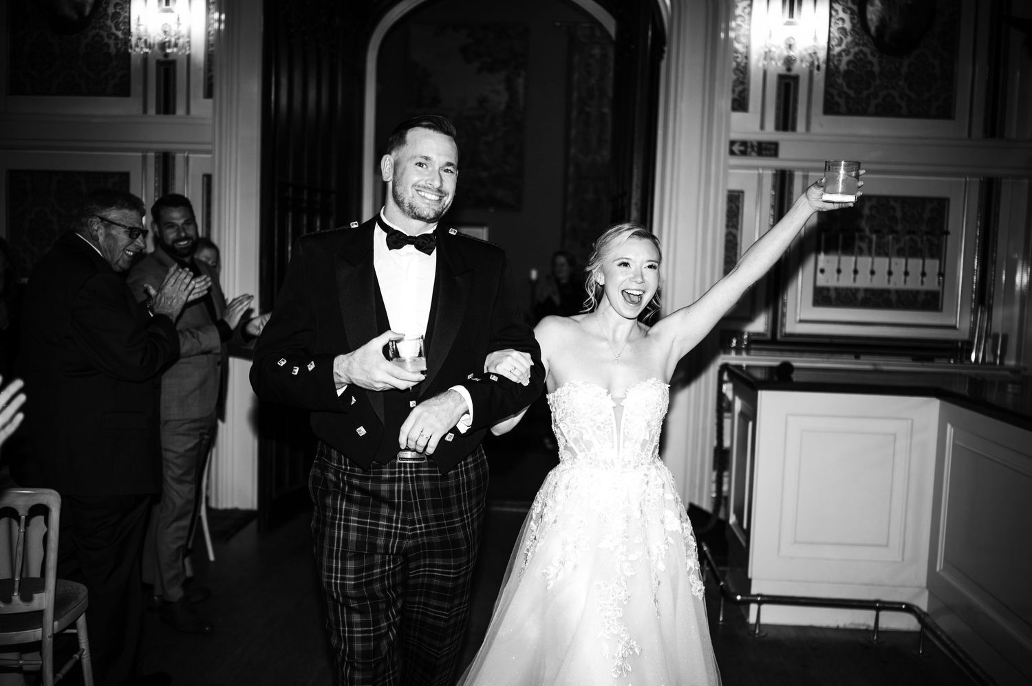 A bride and groom share their first dance at an elegant wedding reception under warm lighting.