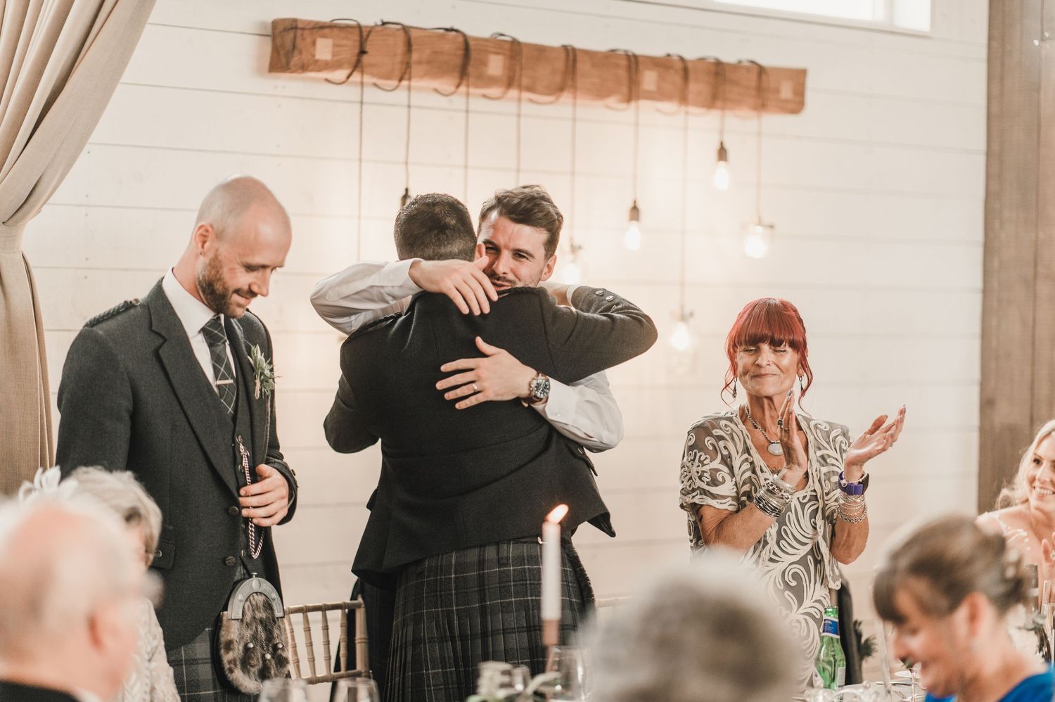An emotional embrace shared during wedding speeches at an elegant reception venue.