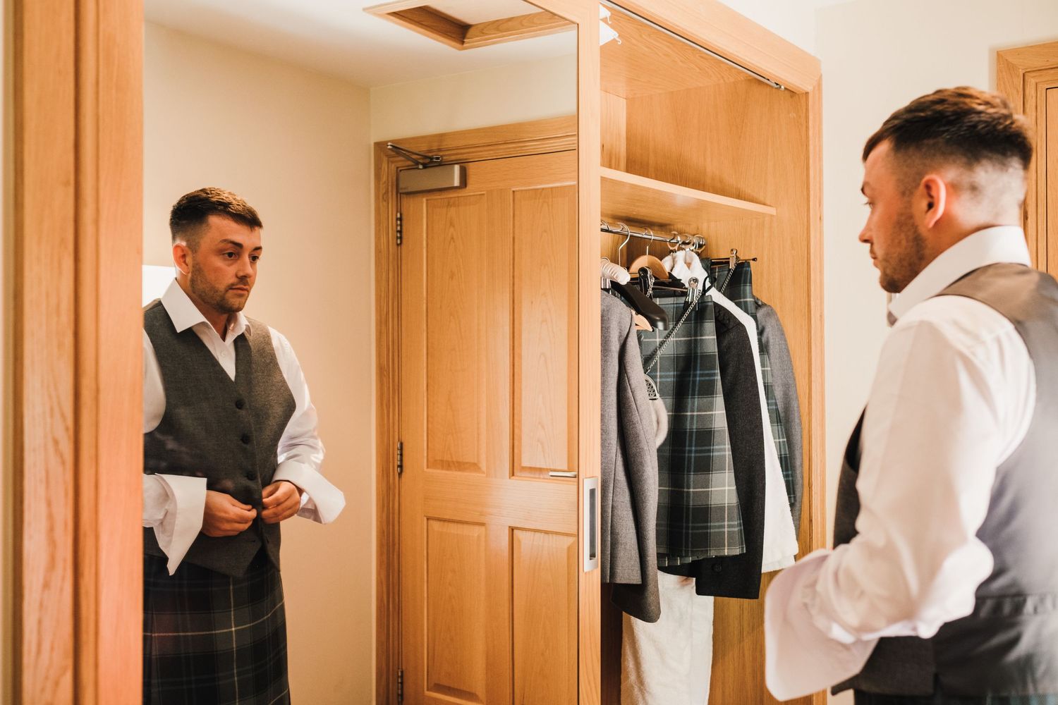 Person in traditional Scottish attire checking their appearance in a mirror.