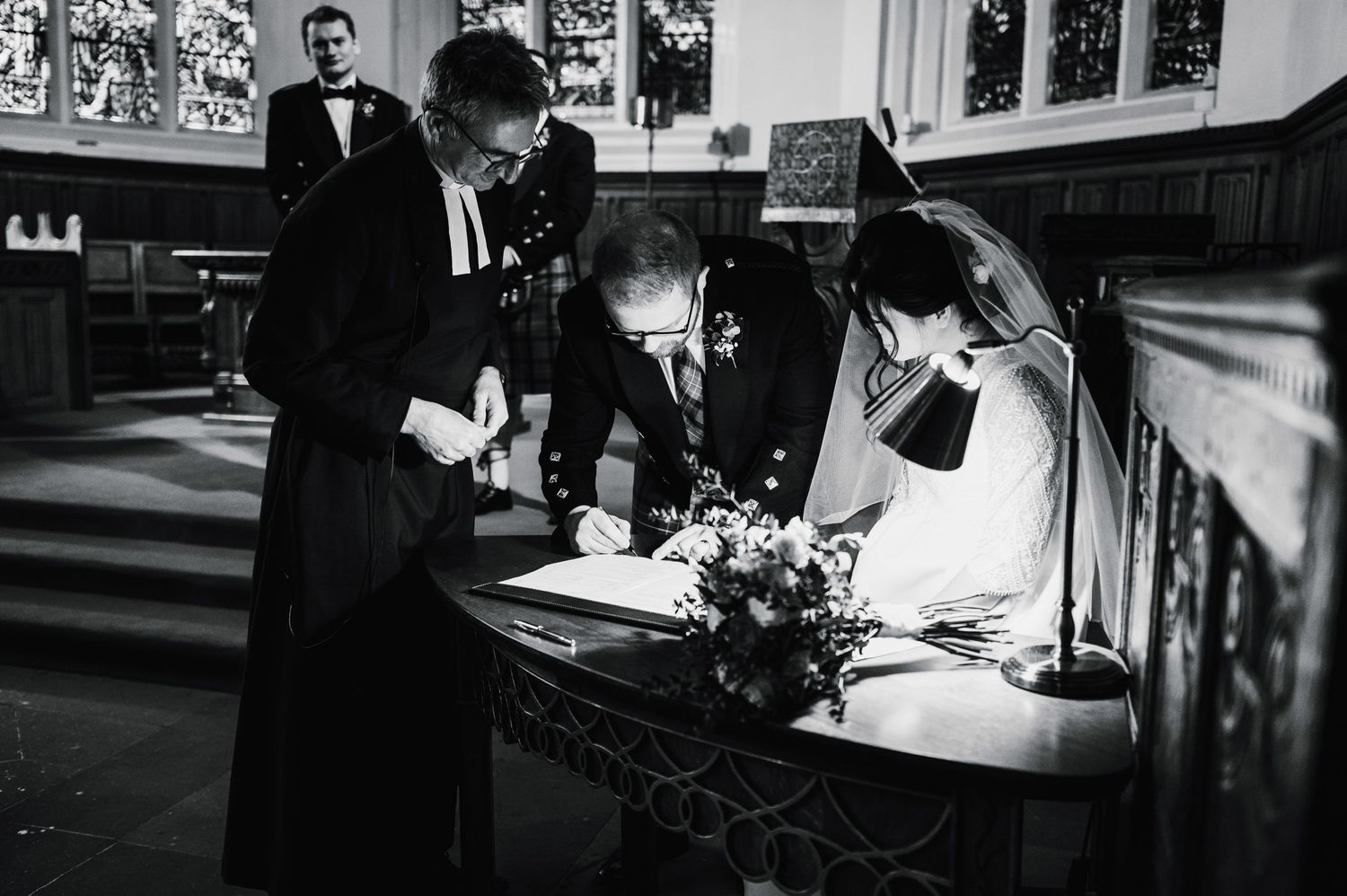 Black and white photo of wedding couple signing marriage register in church.