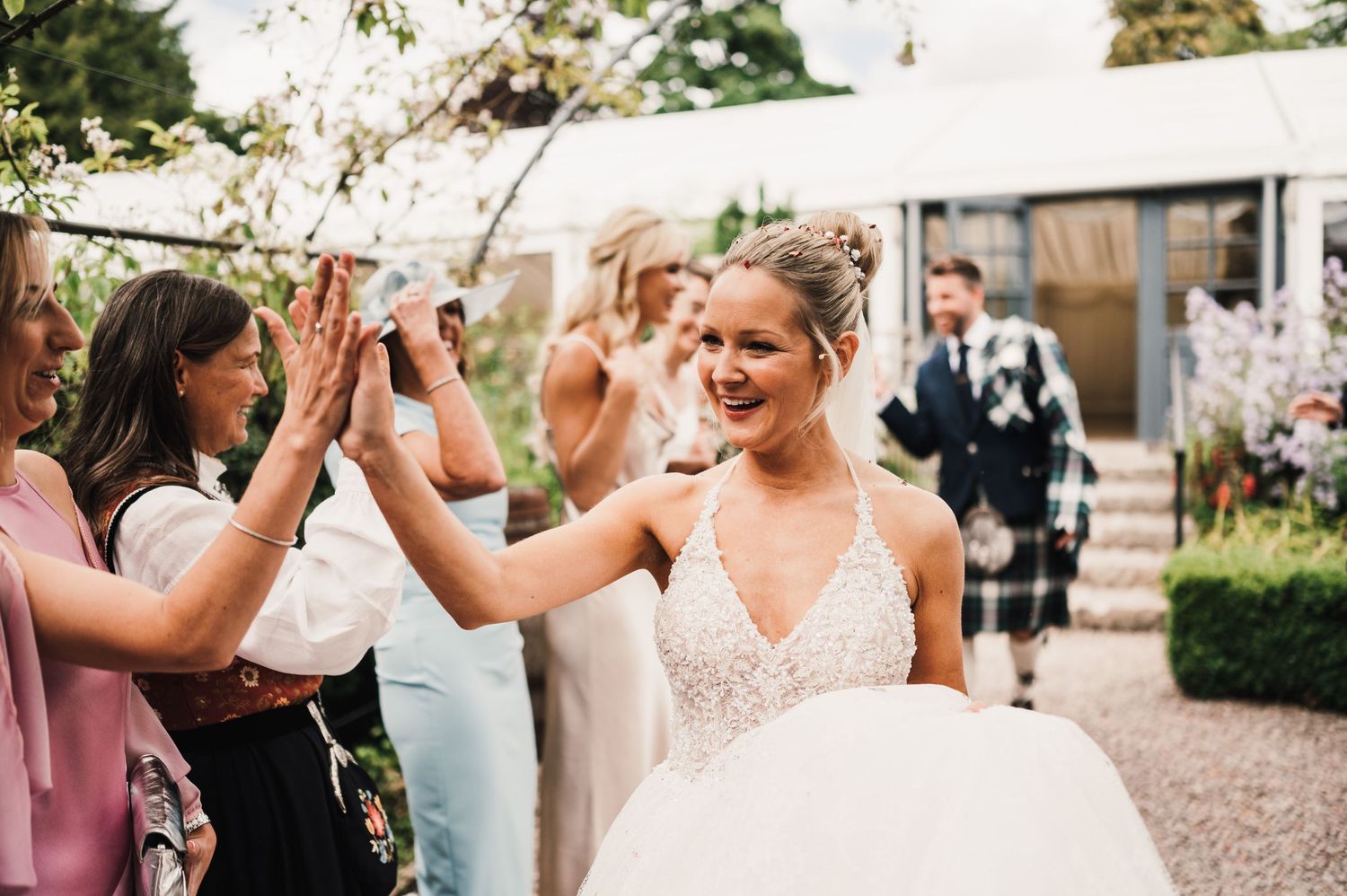 Joyful wedding celebration with guests high-fiving in a garden setting.