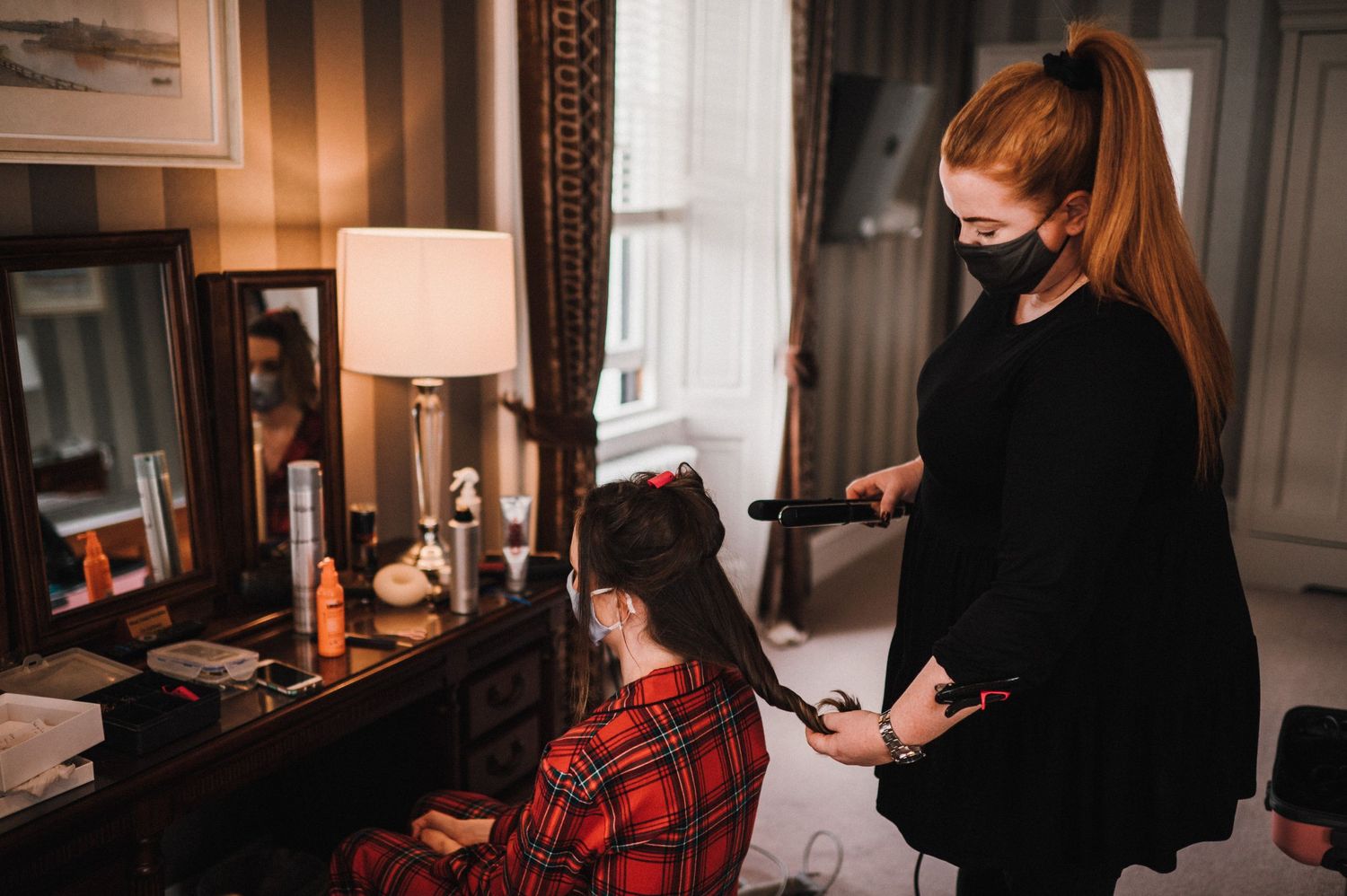 Hair styling session in progress in an elegant room with warm lighting.