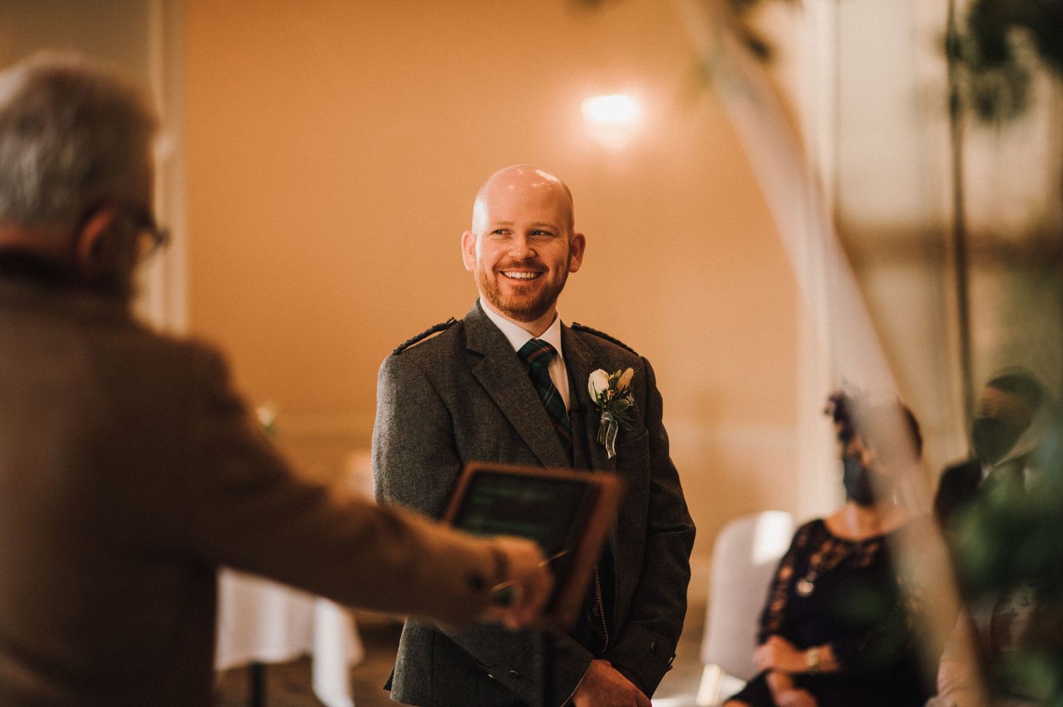 Indoor wedding ceremony with warm lighting and decorative floral arrangements.