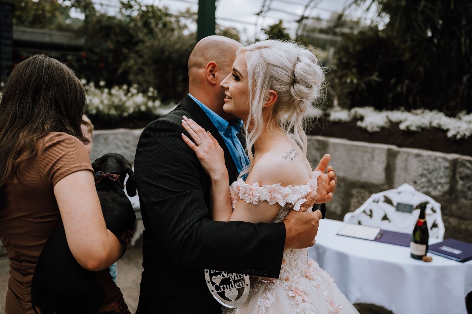A couple shares an intimate moment during their wedding celebration in a garden setting.