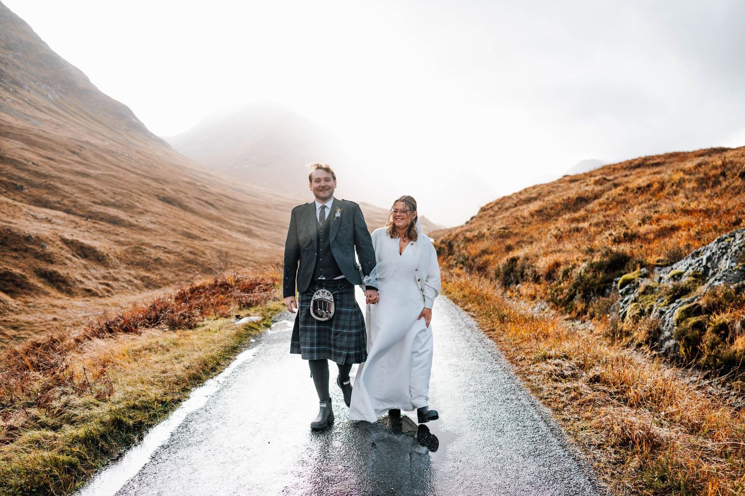 Dramatic Scottish Highland landscape with misty mountains and winding road in autumn colors.