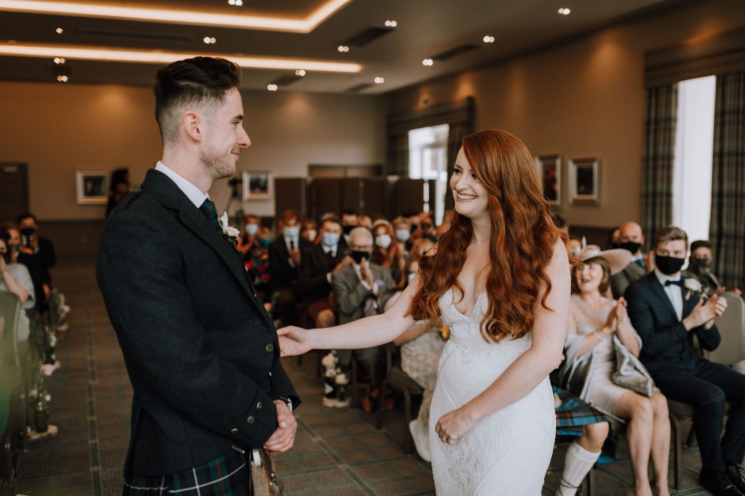 Wedding ceremony in a modern venue with recessed lighting and large windows.