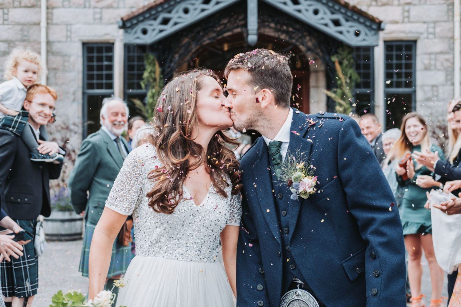 A romantic wedding celebration sequence showing joyful moments between newlyweds and guests at a stone building venue.