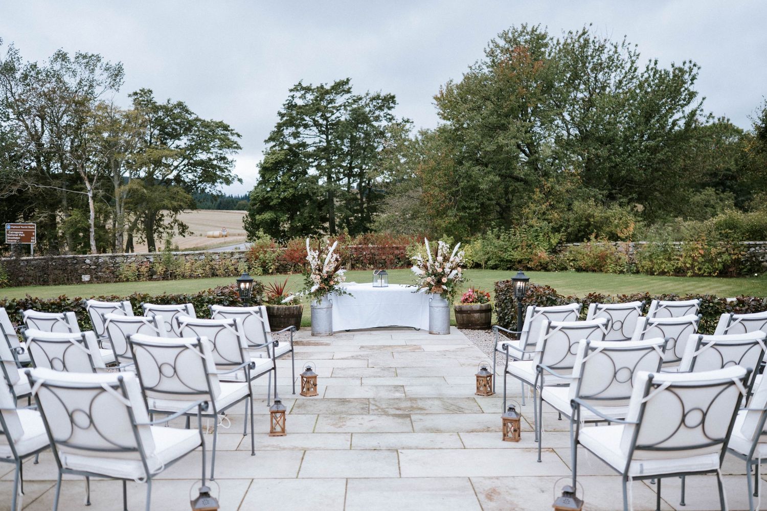 White chairs arranged in rows for an outdoor wedding ceremony with a scenic natural backdrop.