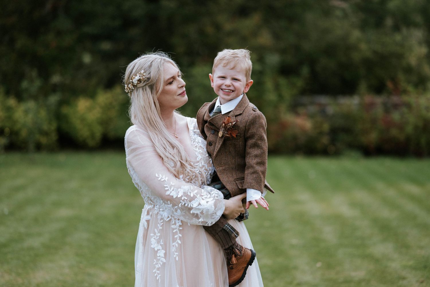 Wedding couple and child sharing intimate moments in a green garden setting.