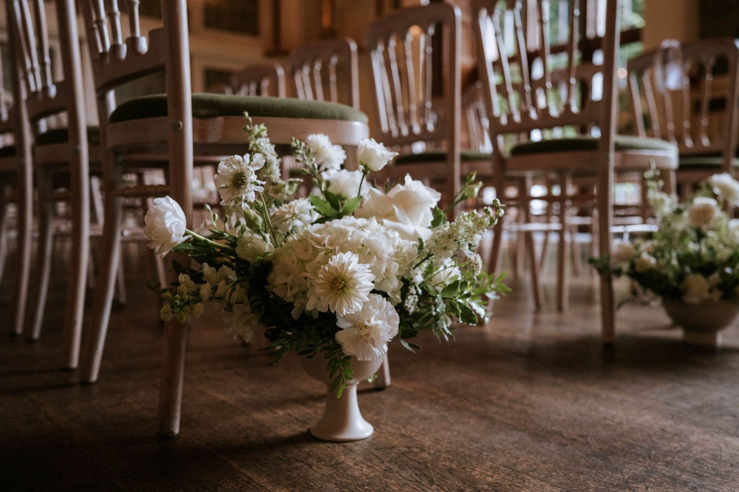 Elegant white floral centerpieces and table settings at wedding reception.