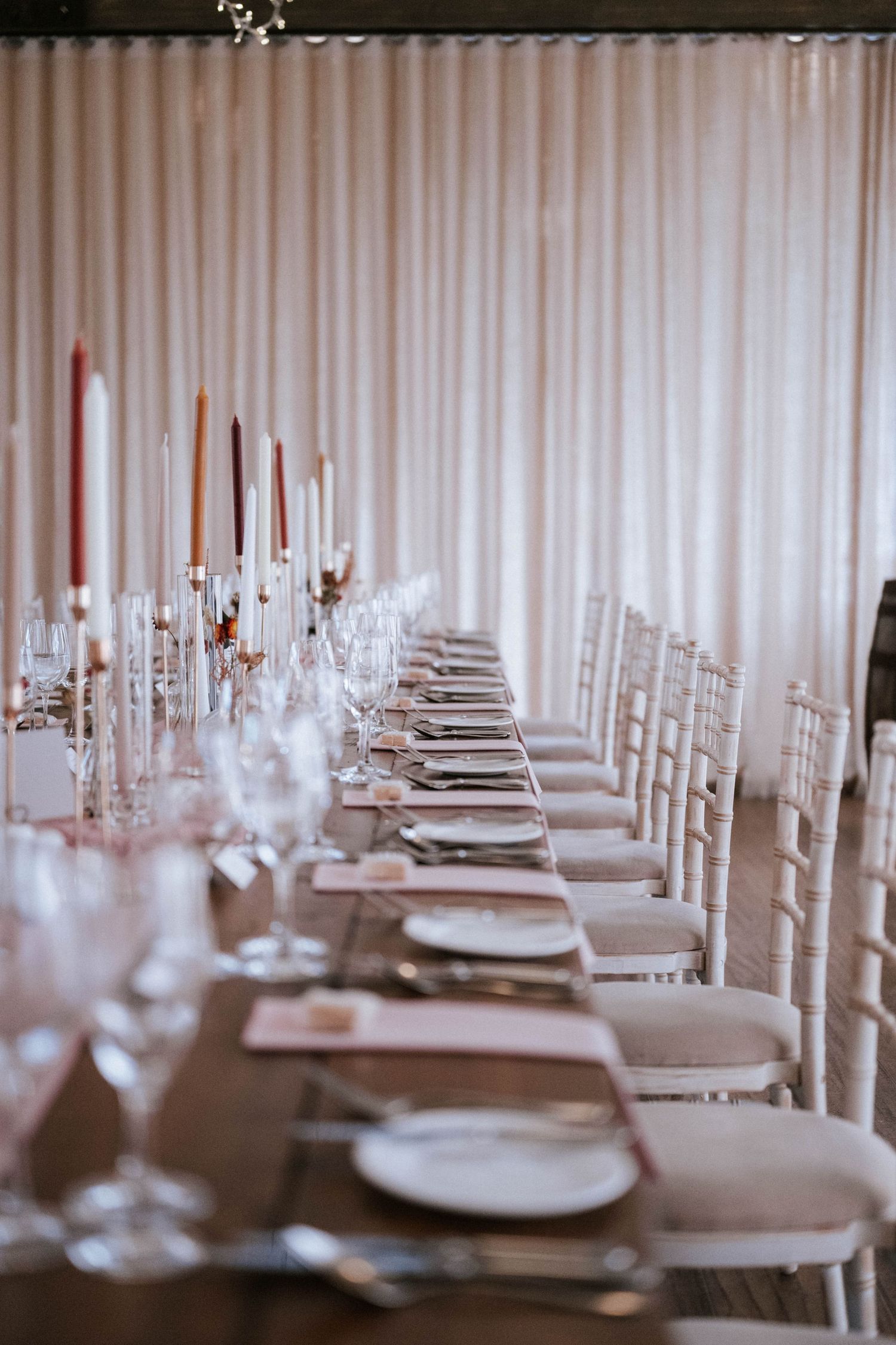 Elegant wedding reception table settings with white linens and tall candles.