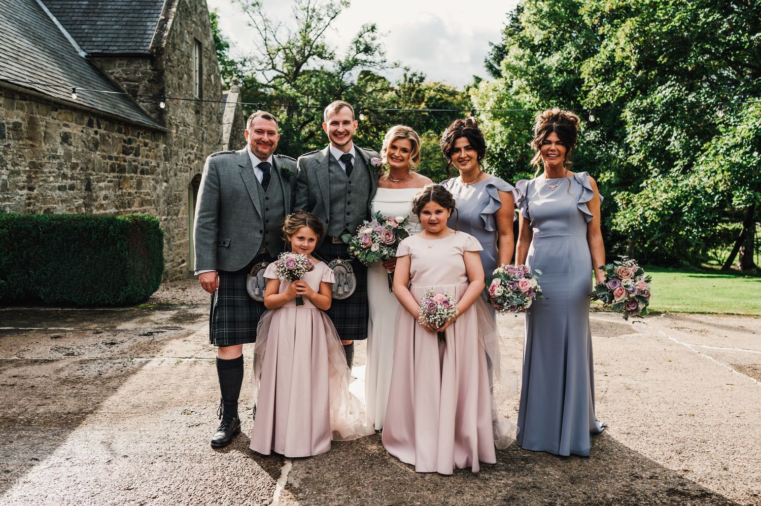 Wedding party in blue and pink dresses posing outside historic building.