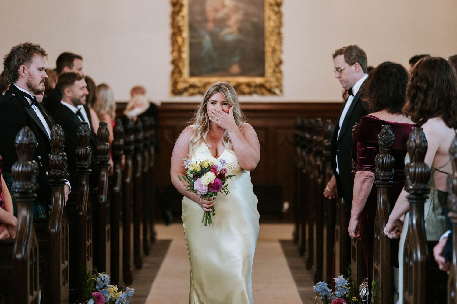 Wedding ceremony processional in historic church with wooden pews.