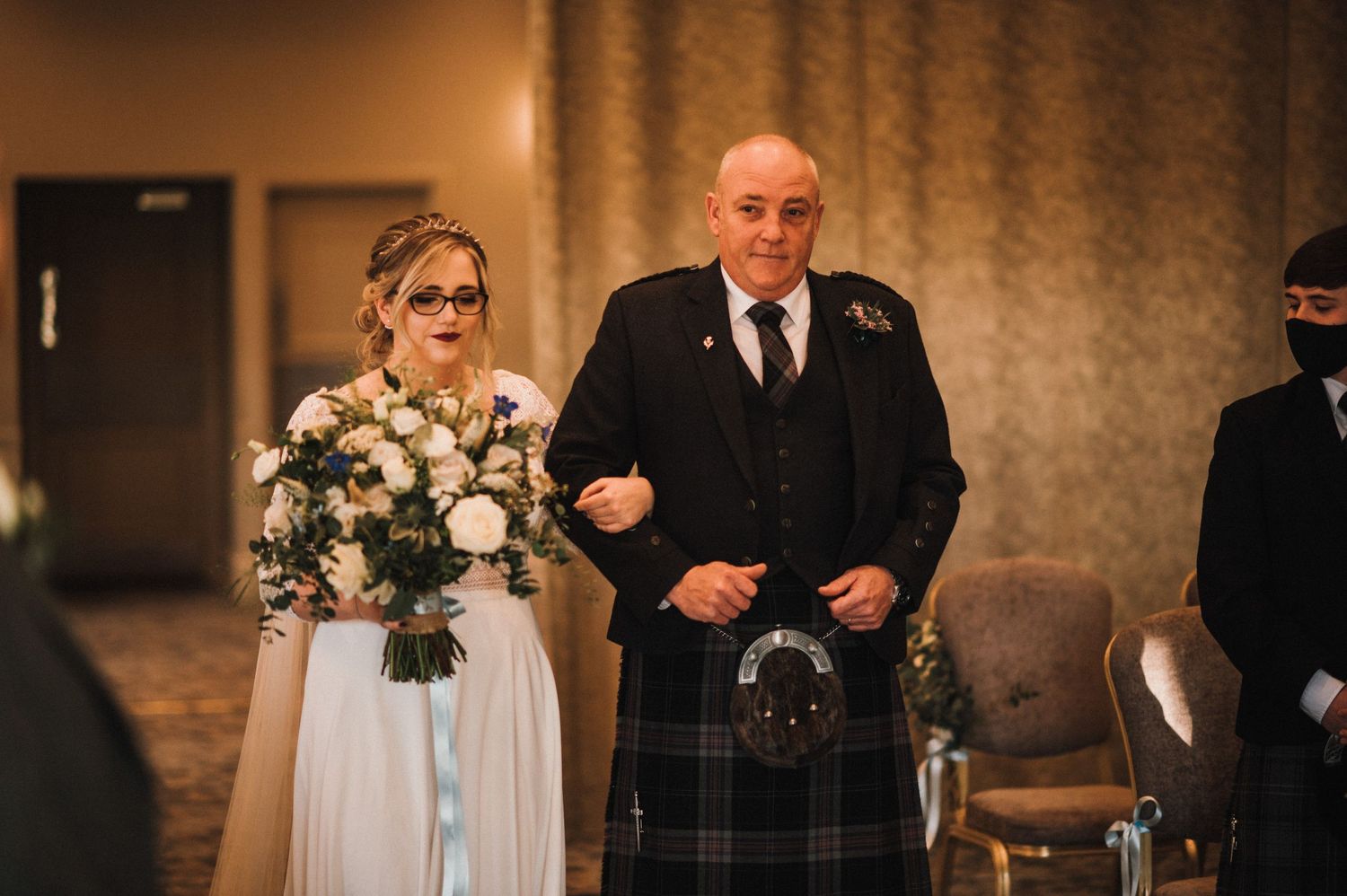 Traditional Scottish wedding ceremony with kilt-wearing participant walking down the aisle.