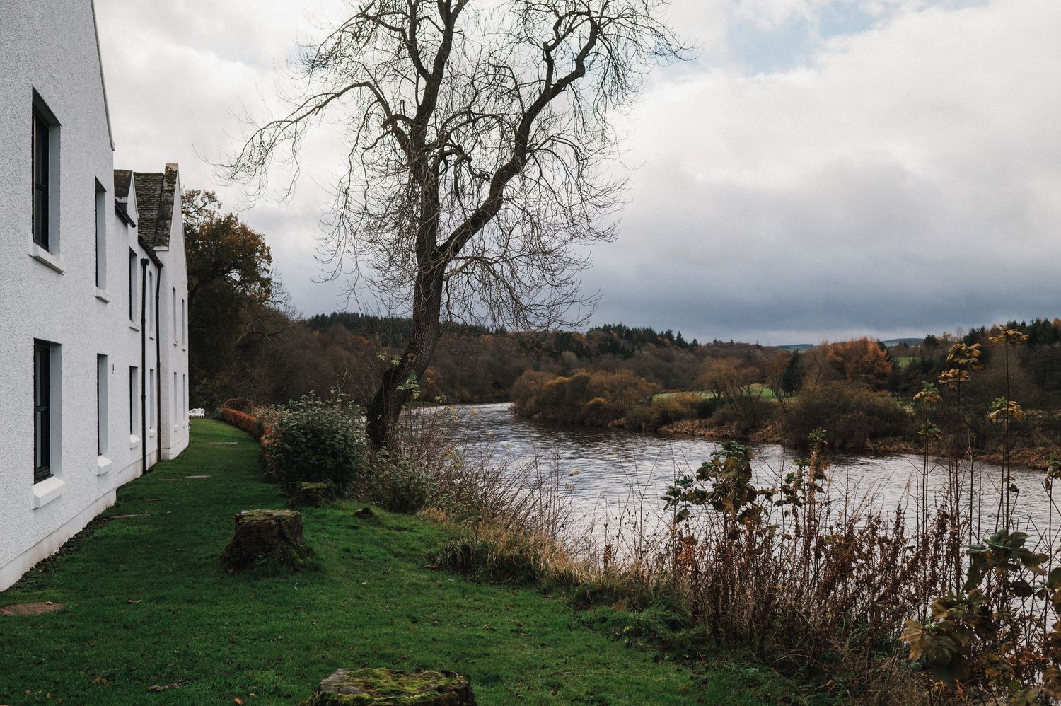 White buildings overlooking a serene lake with moody autumn landscape.