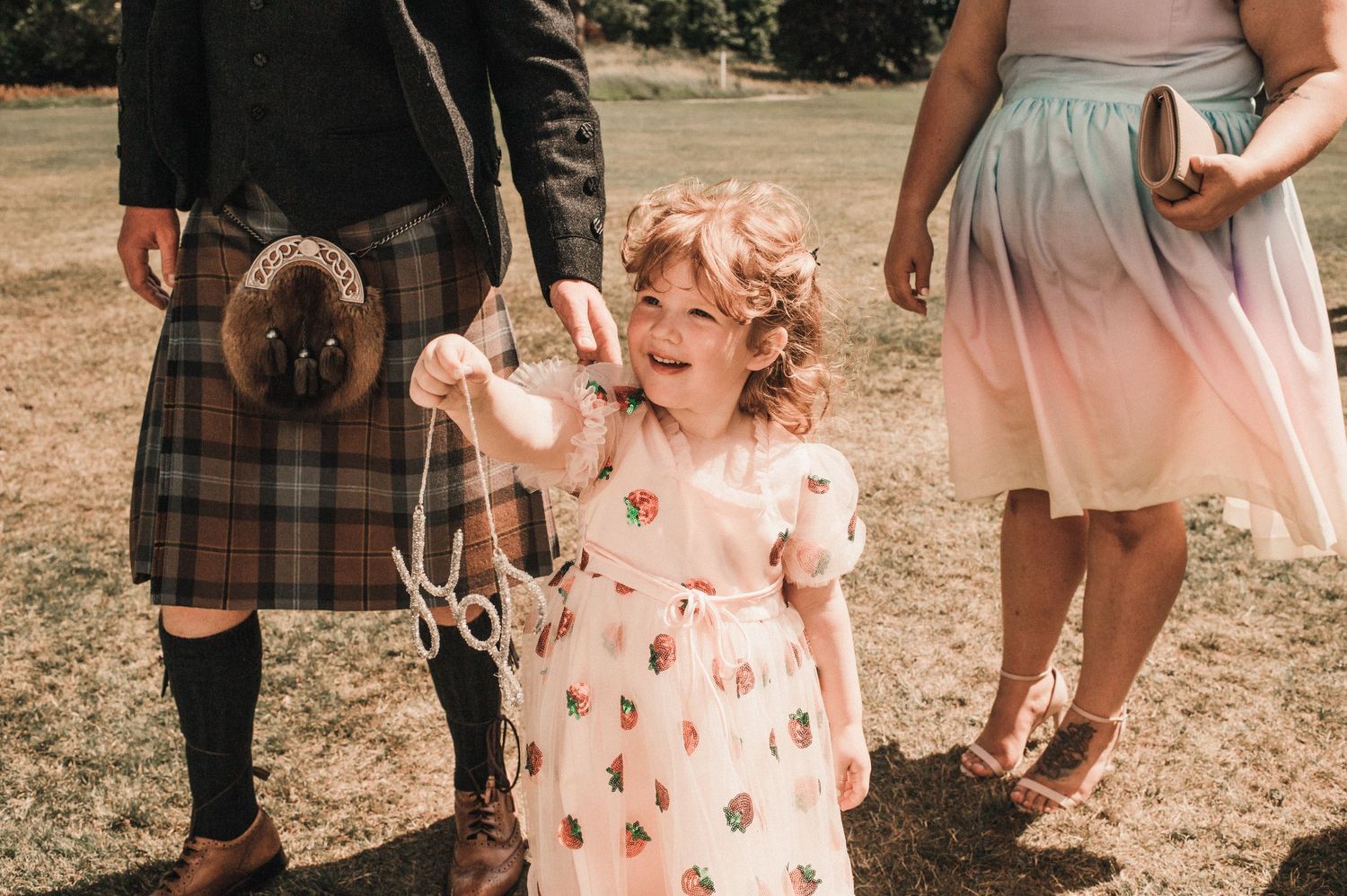 Young child in floral dress enjoying festivities at outdoor wedding celebration.