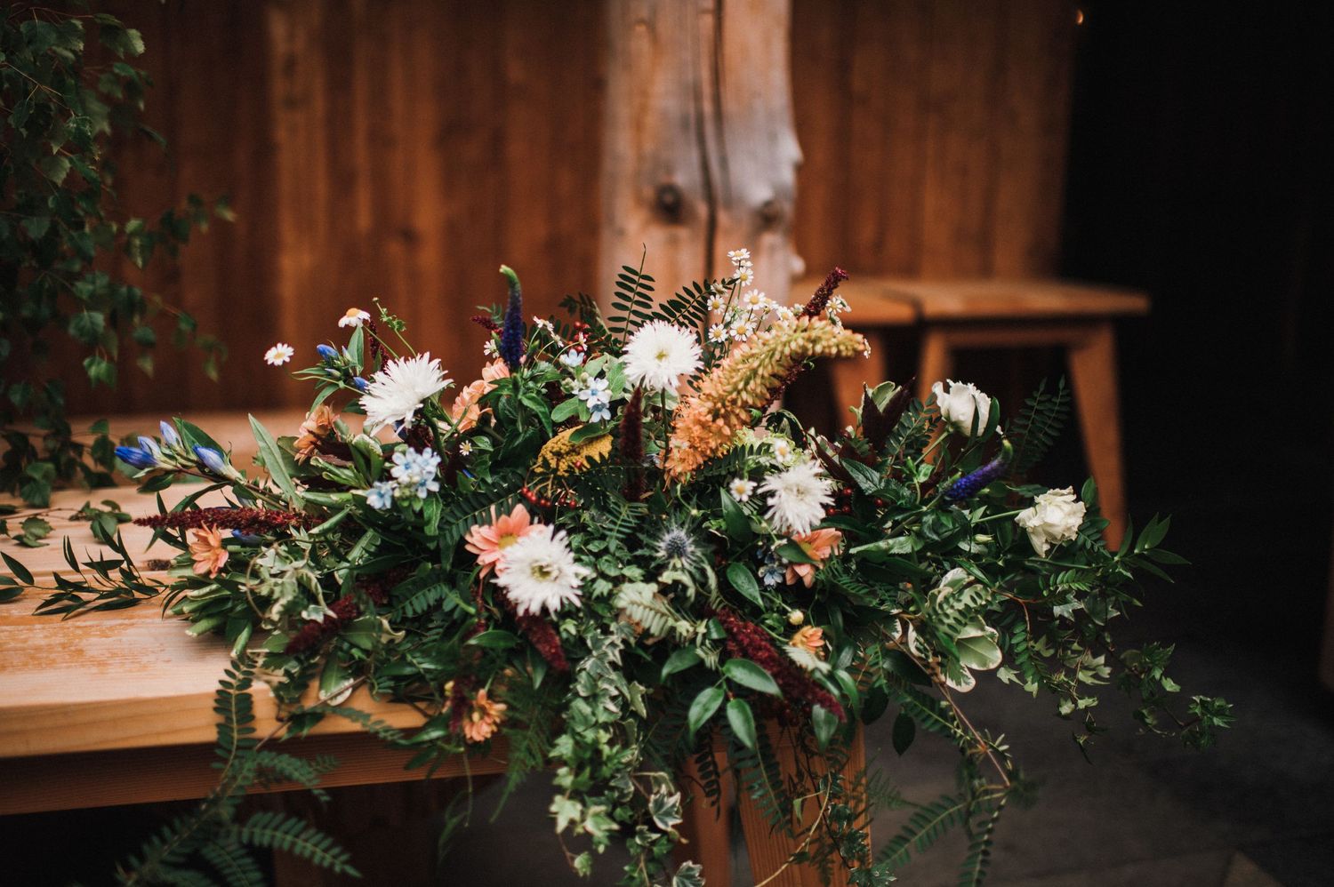 Elegant floral arrangement with white flowers and greenery on wooden surface.