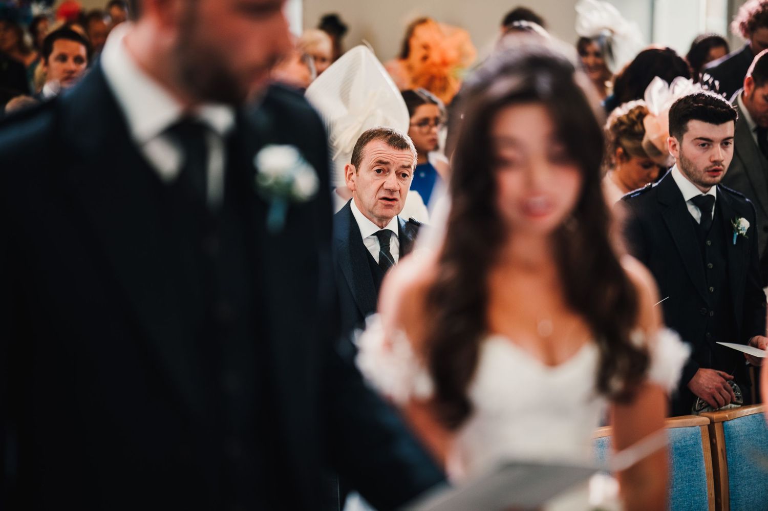 Candid moment captured during wedding ceremony in church with guests and wedding party.
