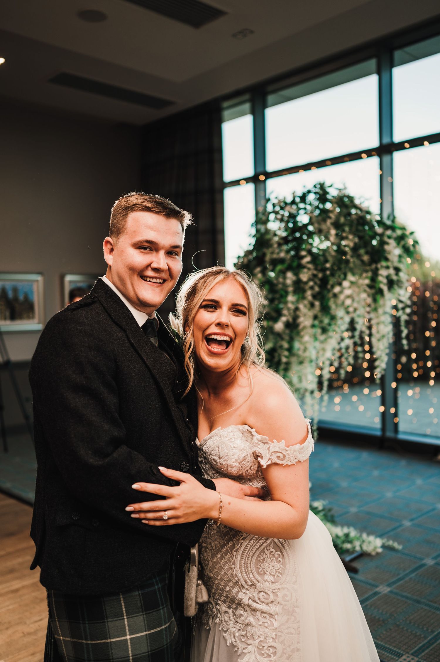 Joyful moment captured at wedding reception with Scottish formal wear and elegant decor.