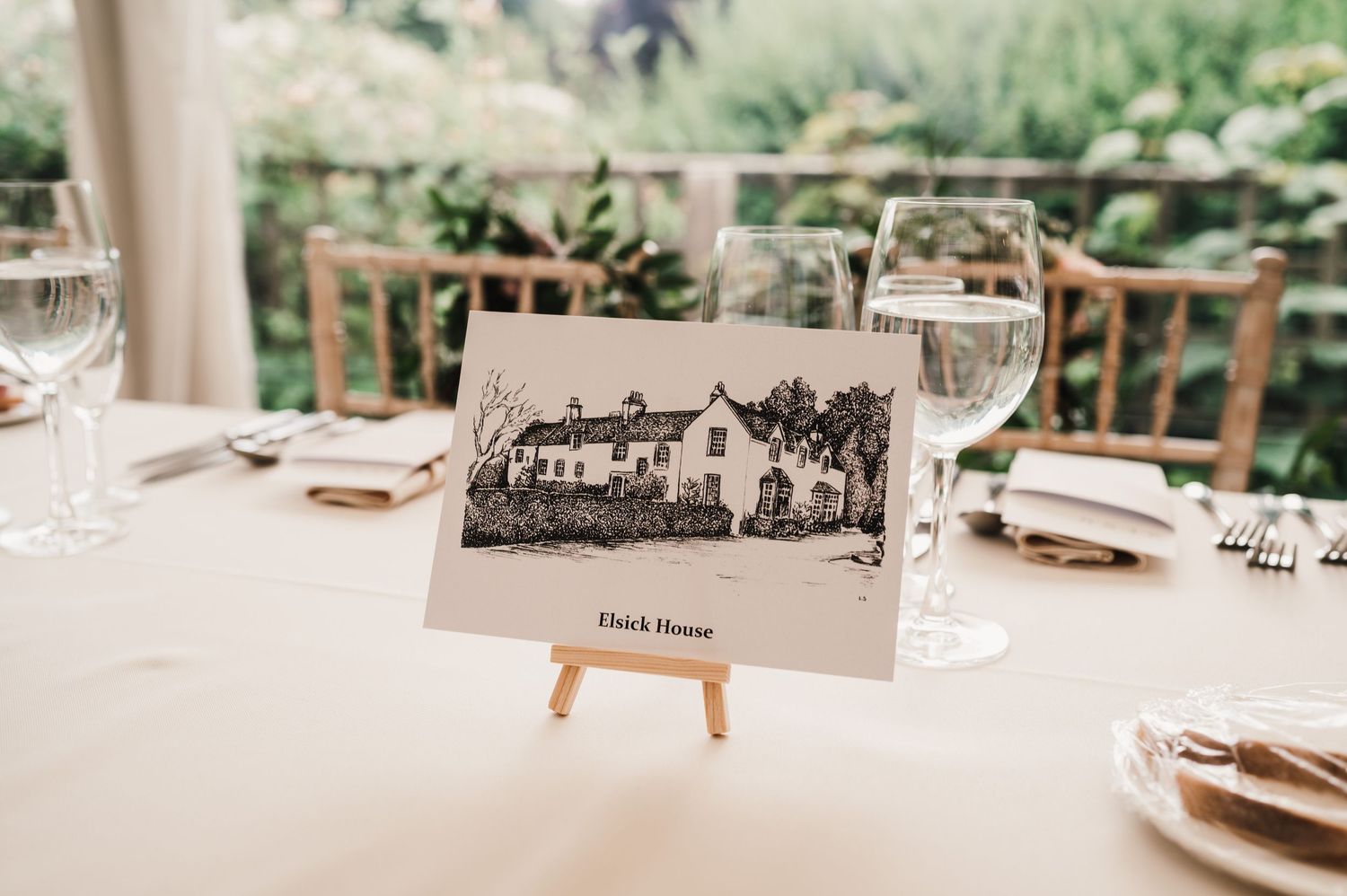 Black and white photo of a mansion displayed on an easel at an elegant table setting.