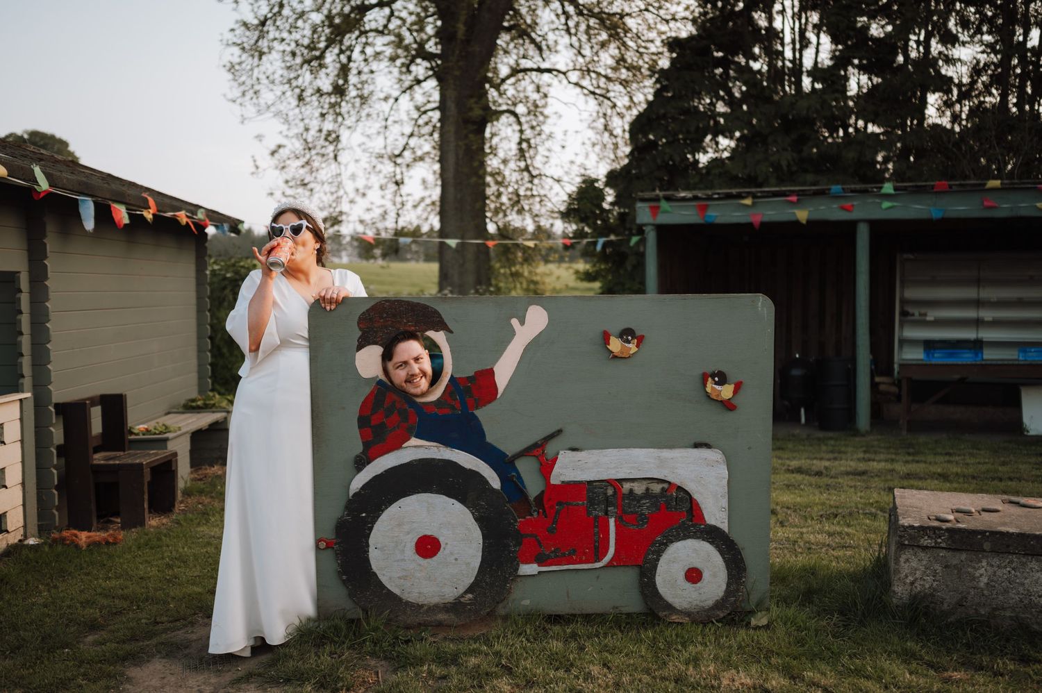 Fun wedding photo with painted tractor photo backdrop in garden setting.
