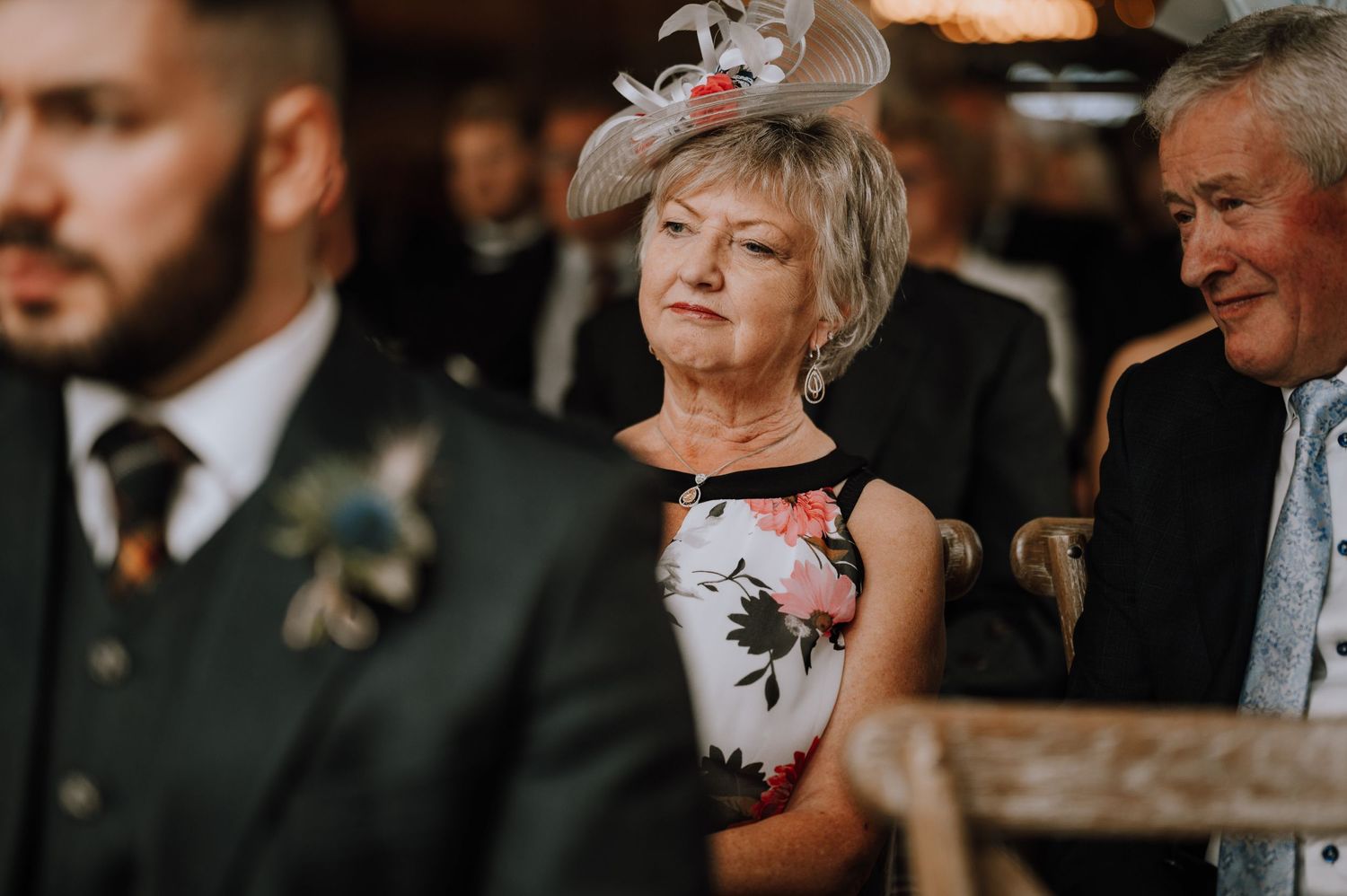 Wedding guests in formal attire gathered for the ceremony in rustic venue.