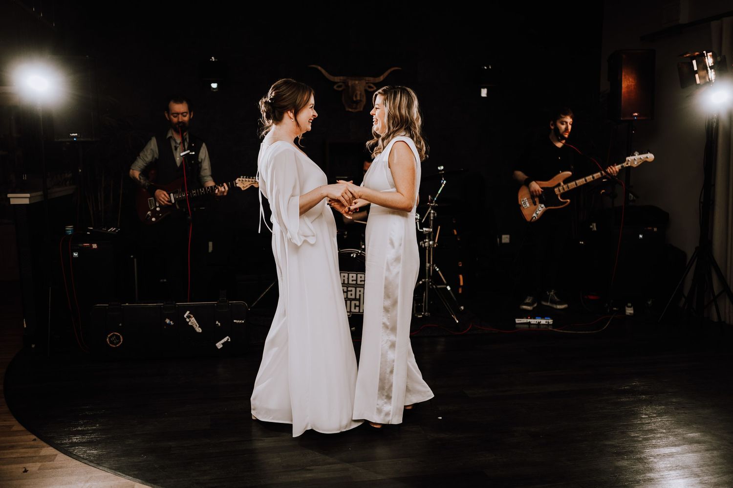 Same Sex Wedding Photography. Guests dancing and celebrating at a dimly lit wedding reception with moody lighting.