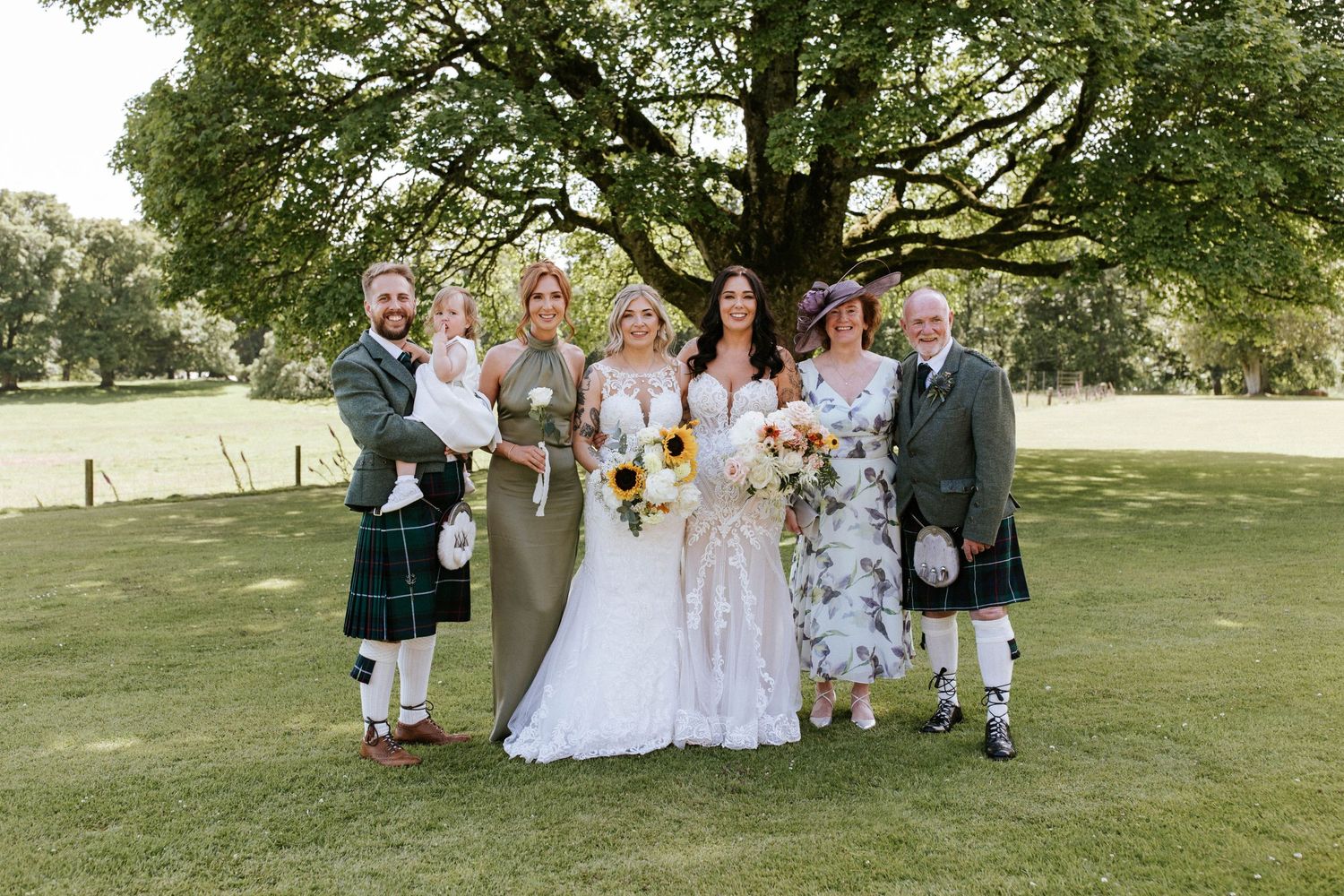 Fasque Castle Wedding Photography. Wedding party members gather for formal portraits under a sprawling tree.