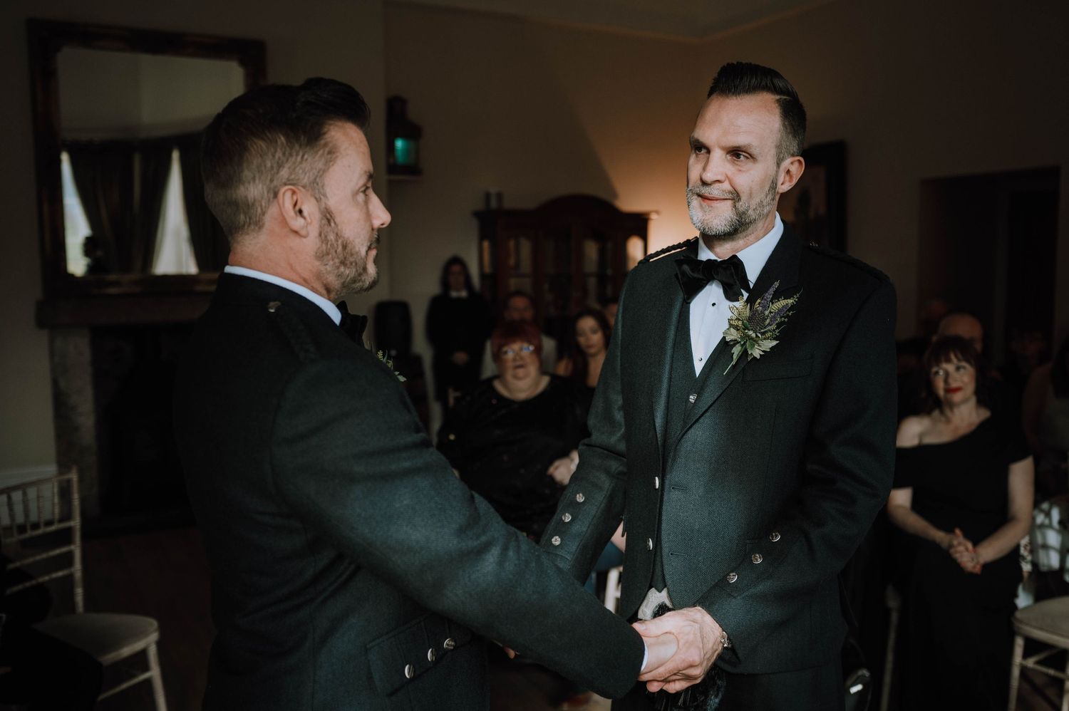Logie House Wedding Photography. Two people in formal black attire share an intimate moment during a wedding ceremony.
