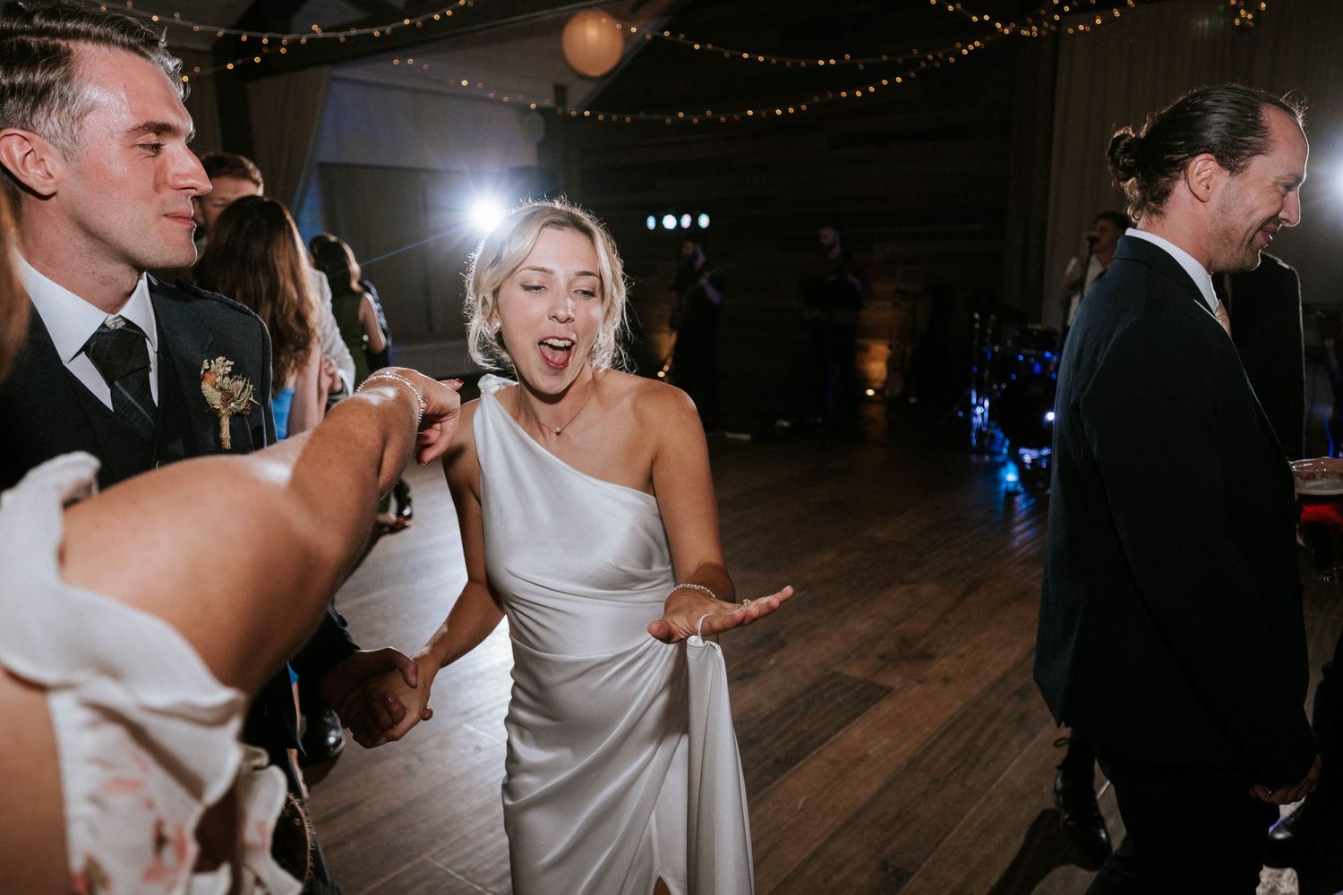 Wedding celebration on dance floor with string lights overhead.