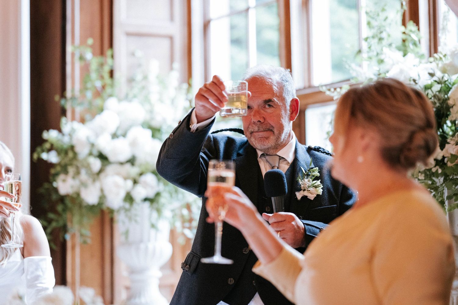 Wedding guests raise their glasses in a celebratory toast during an indoor reception.