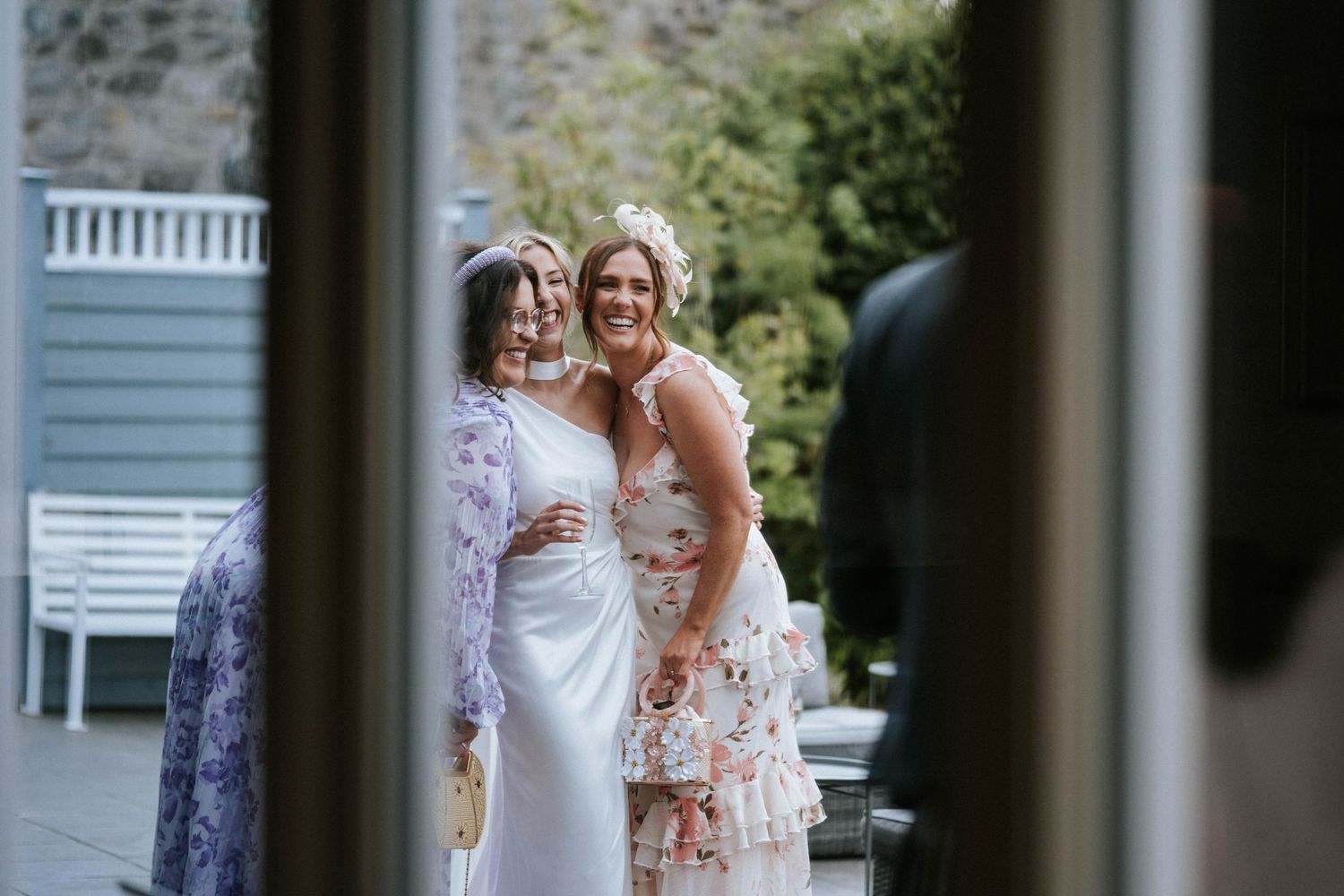 Wedding celebration moment captured through window frame with garden backdrop.