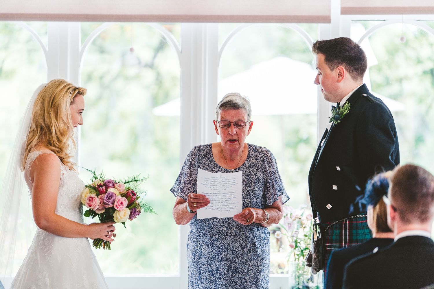 Indoor wedding reception with guests mingling in natural light-filled space.