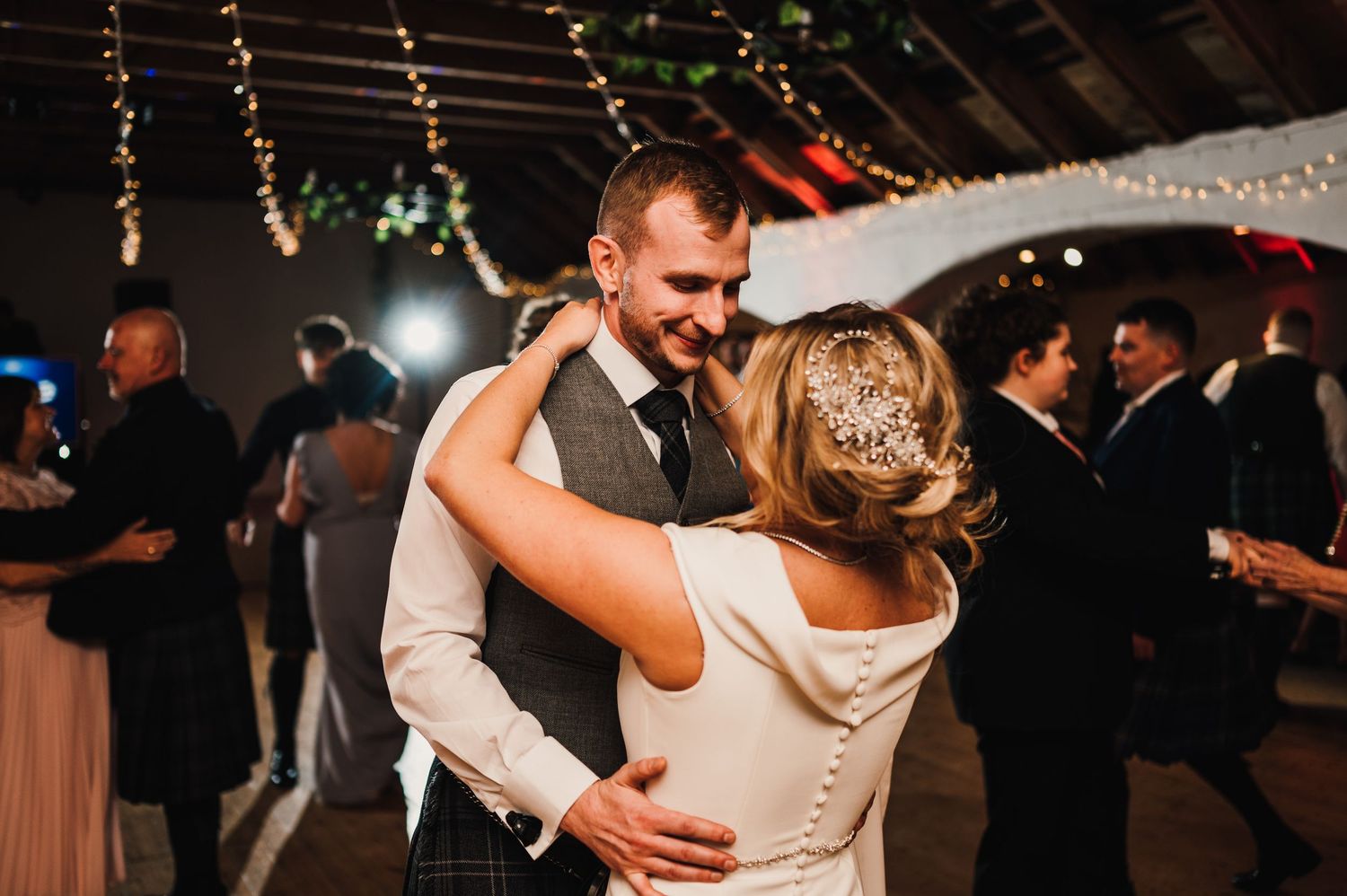 Couple sharing an intimate dance moment under twinkling lights at their wedding reception.