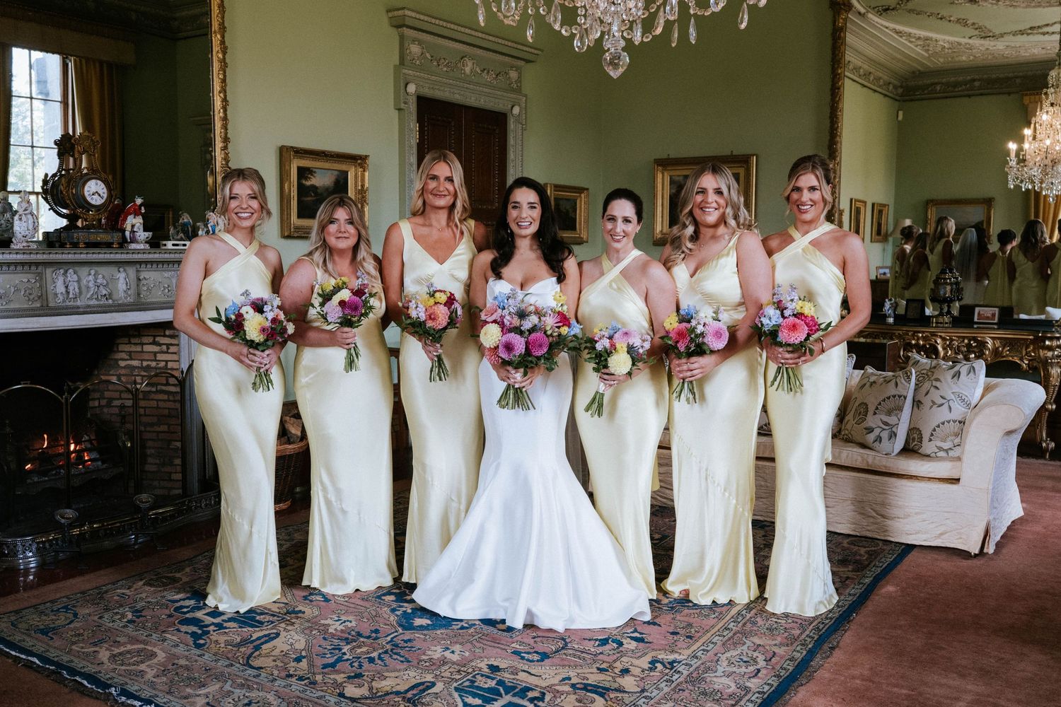 Wedding party in white dresses posing together in an elegant indoor venue.