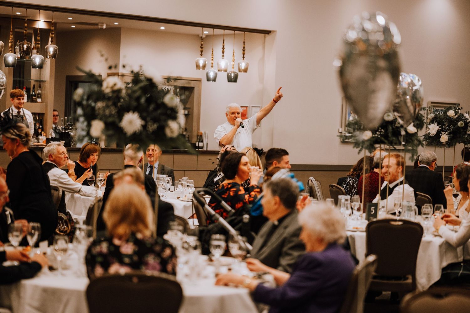 Wedding reception guests celebrate with raised arms during evening party festivities.