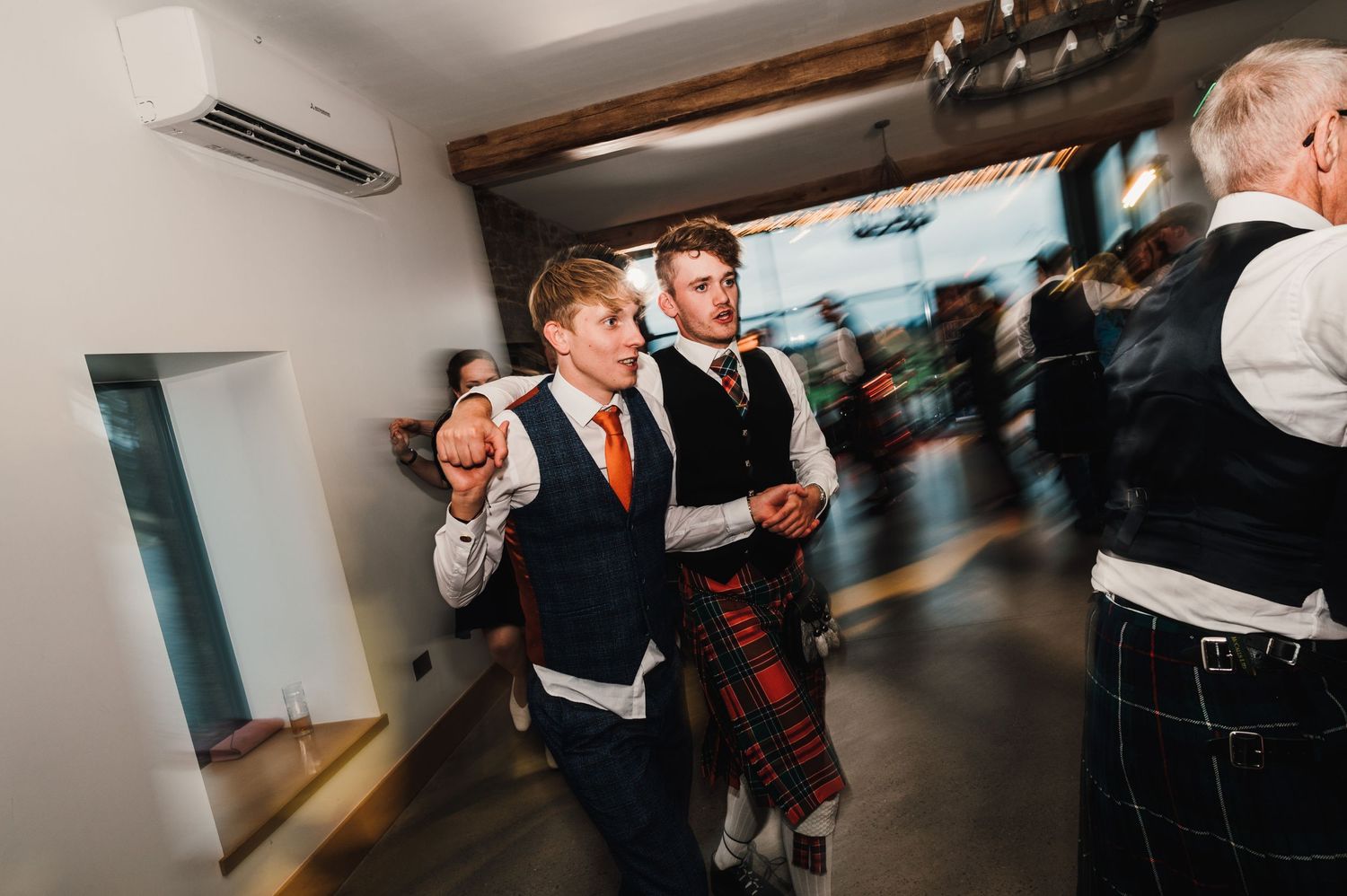 Group of formally dressed guests celebrating at a Scottish wedding reception.