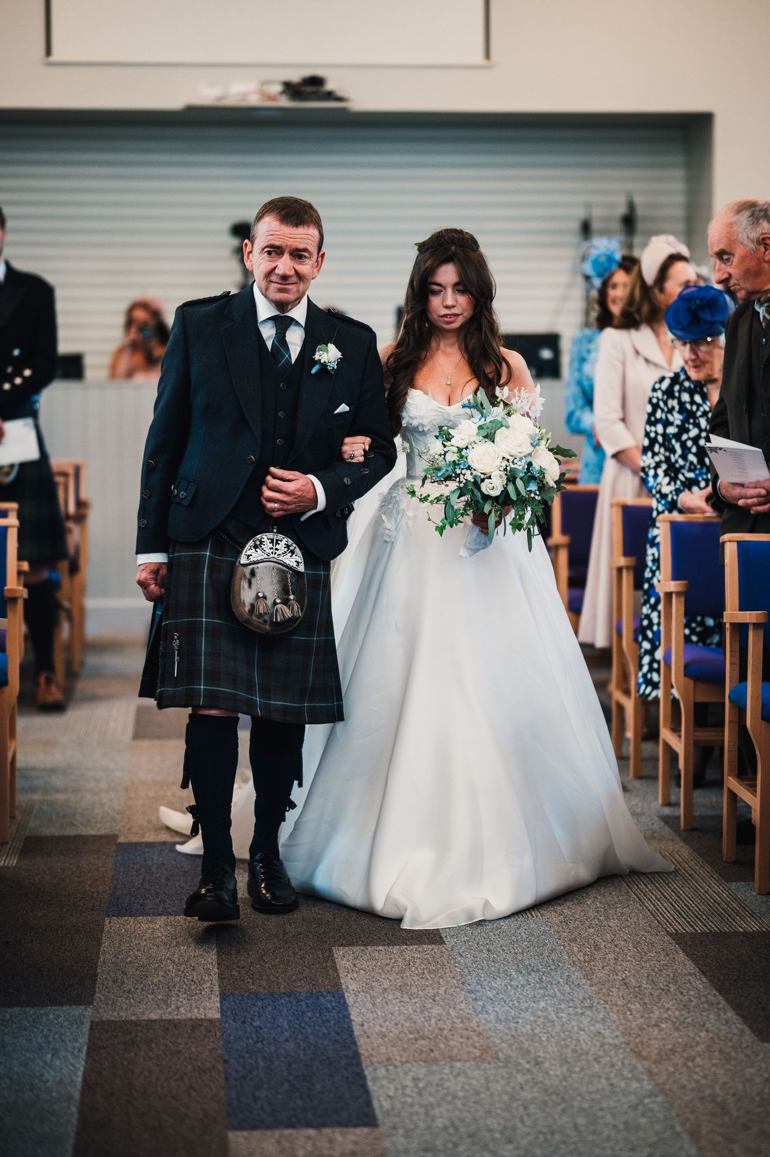 Traditional Scottish wedding processional with man in kilt walking down church aisle.