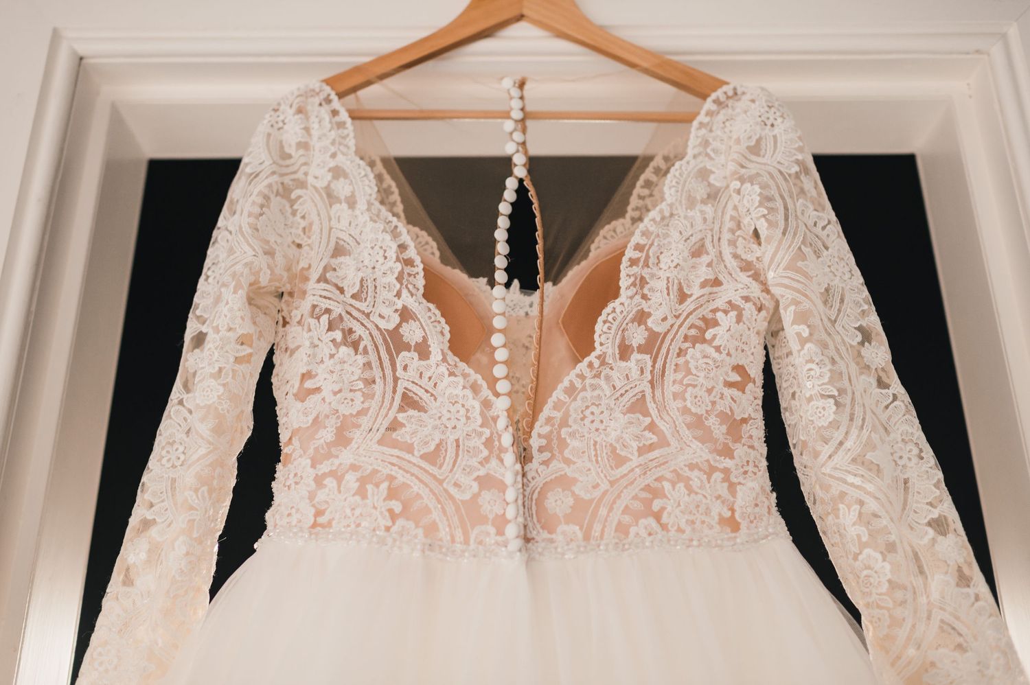 Detailed close-up of a wedding dress bodice showing intricate lace pattern and deep V neckline.