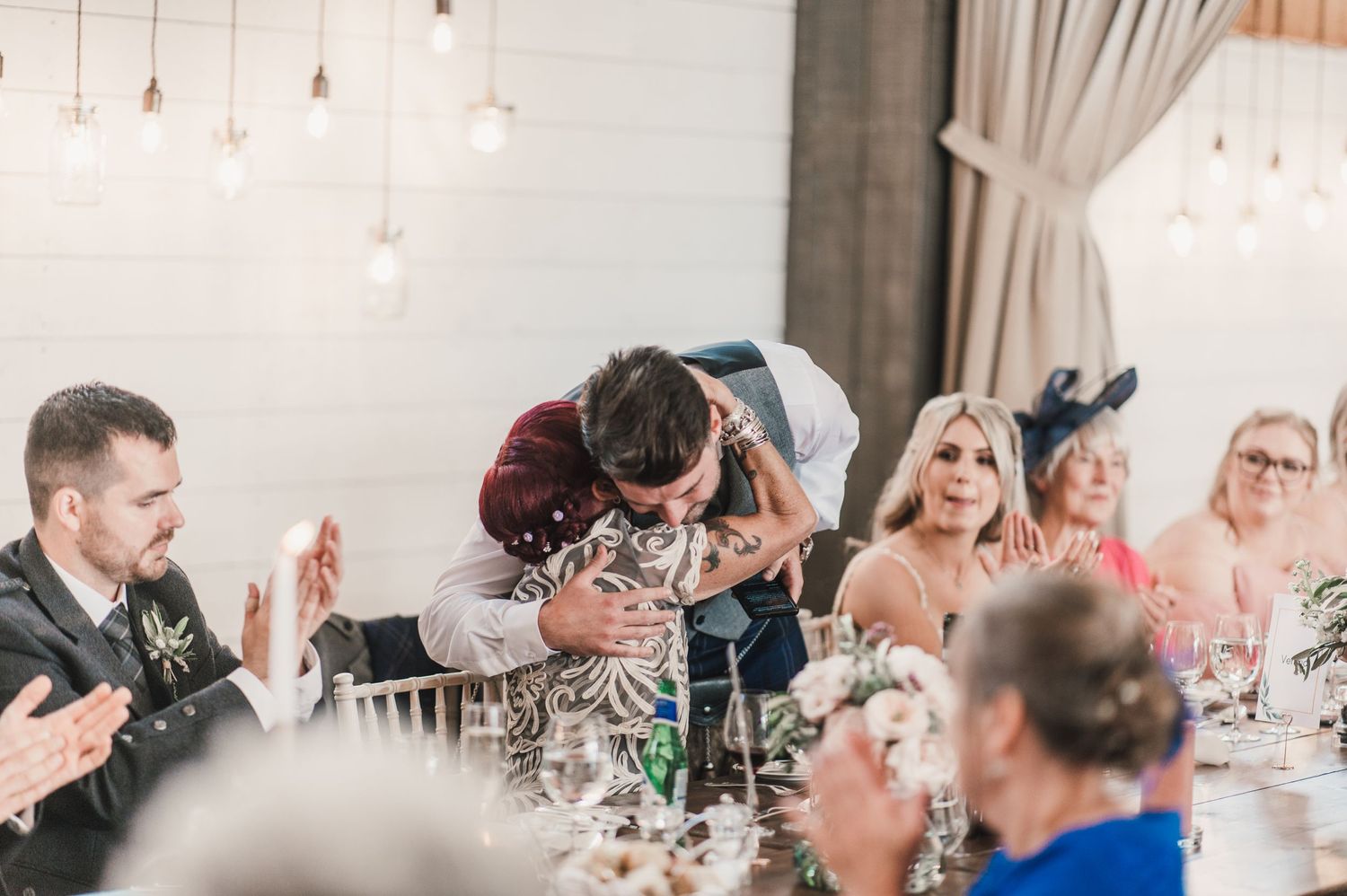 Wedding reception guests reacting with joy and laughter during dinner speeches.