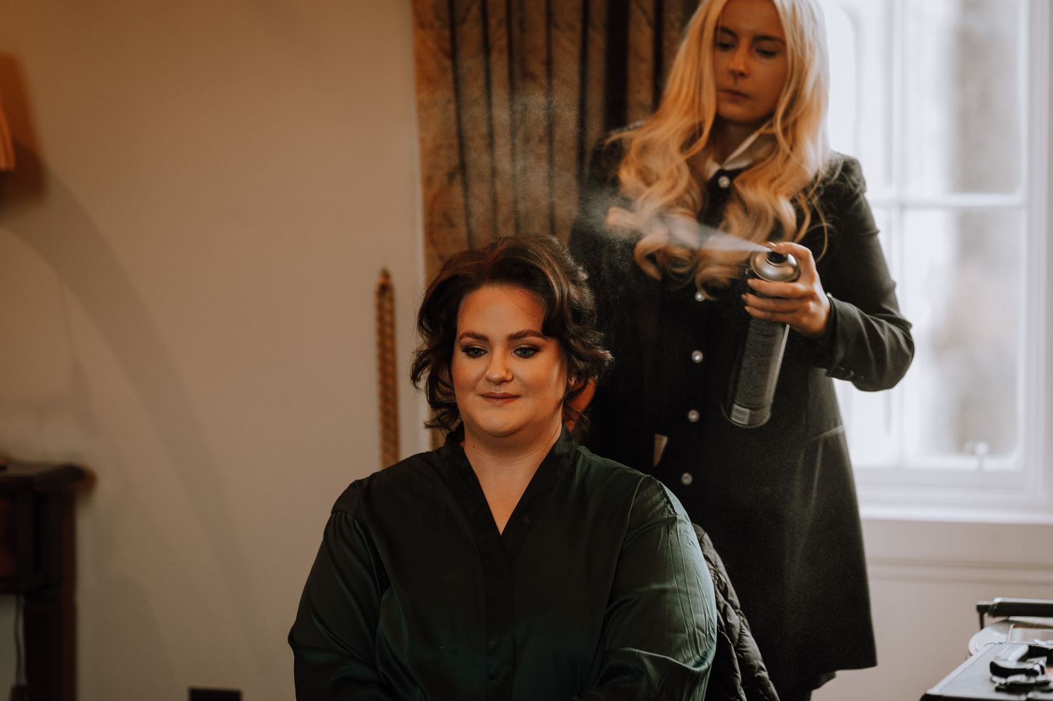 Getting ready scene showing hair and makeup preparations in a softly lit room.