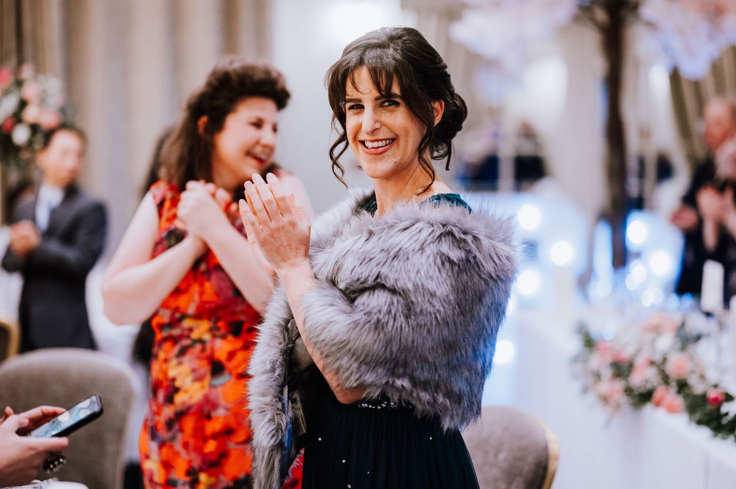 Wedding guests celebrating and dancing in elegant attire at an indoor reception.