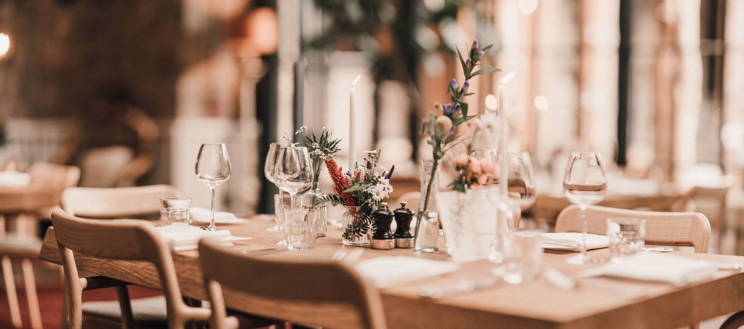 Elegant table setting with glassware and floral centerpieces in a rustic dining room.