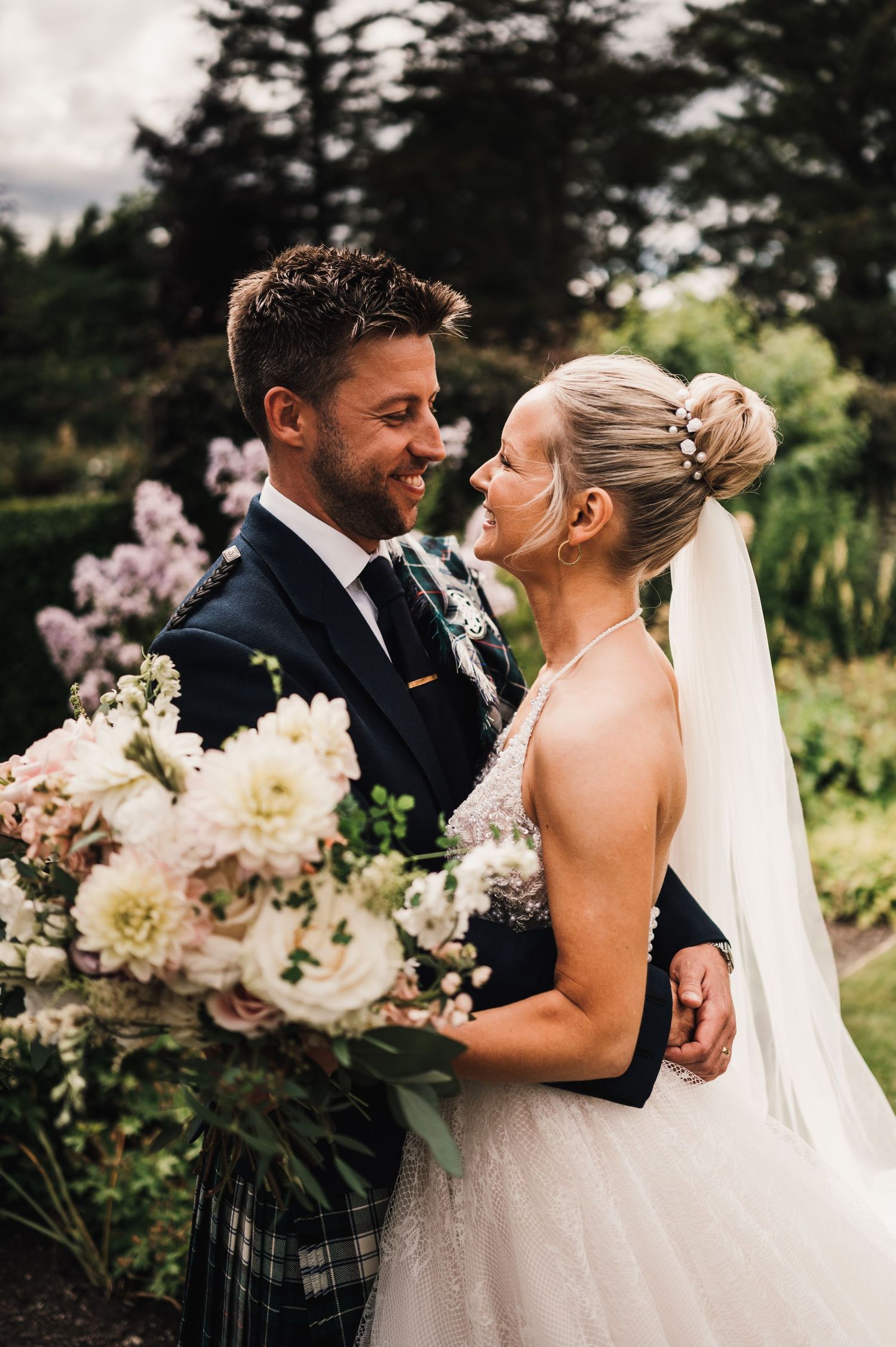A romantic garden wedding moment with elegant florals and Scottish attire.