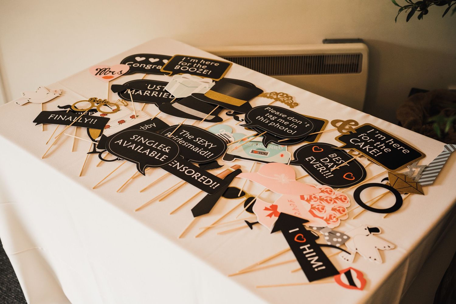 Collection of wedding photo booth props with fun phrases on wooden sticks.