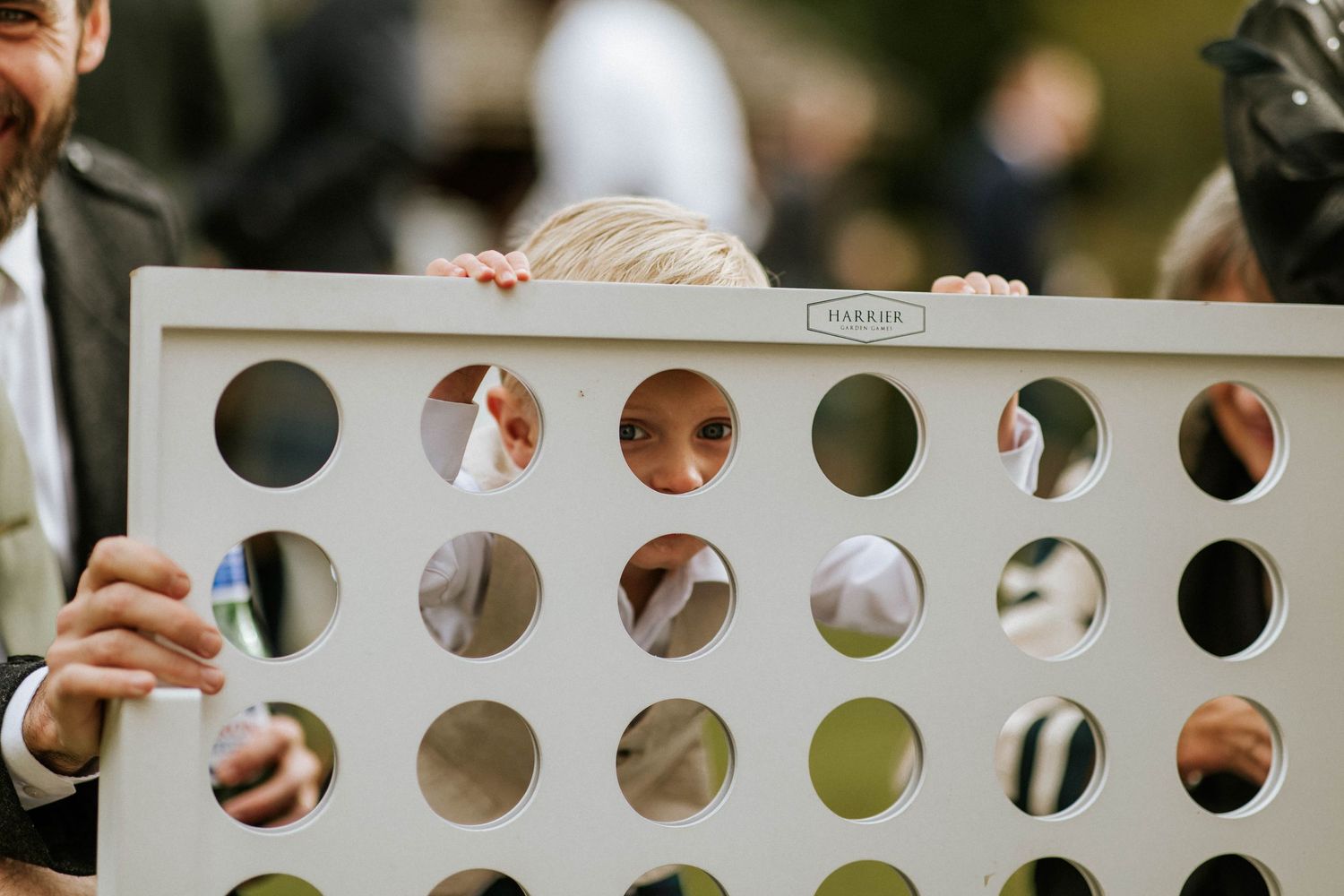 A playful wedding game involving a white board with circular holes being held up.