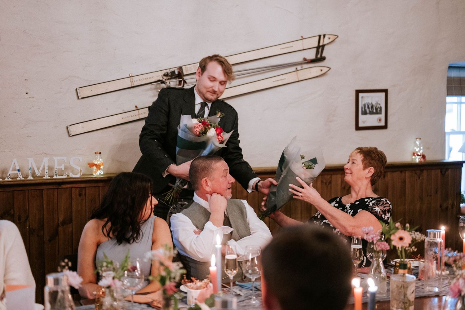 Candlelit dinner party scene showing guests enjoying conversation and drinks at a long table.